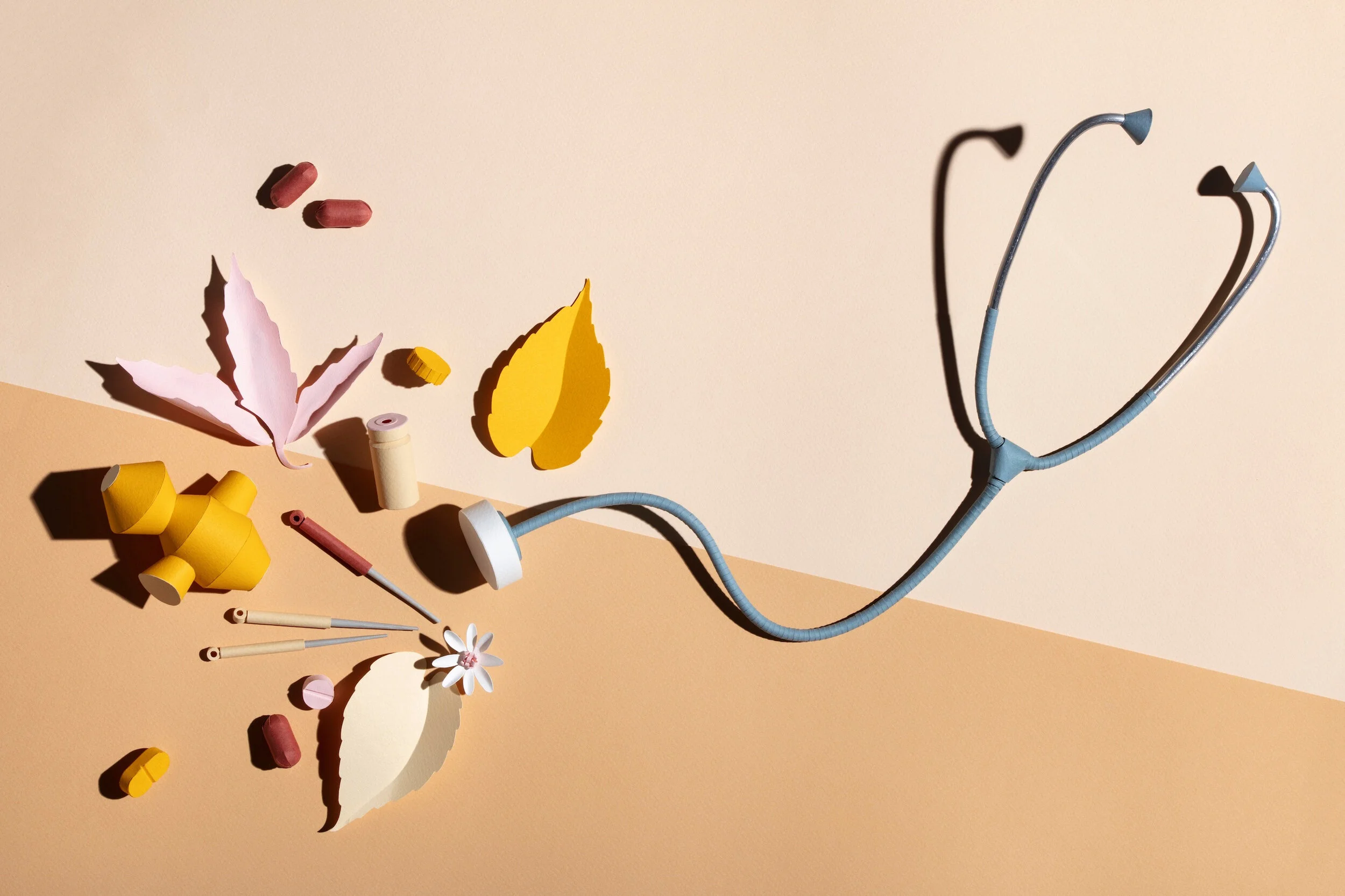 Paper stethoscope surrounded by pieces related to alternative medicine