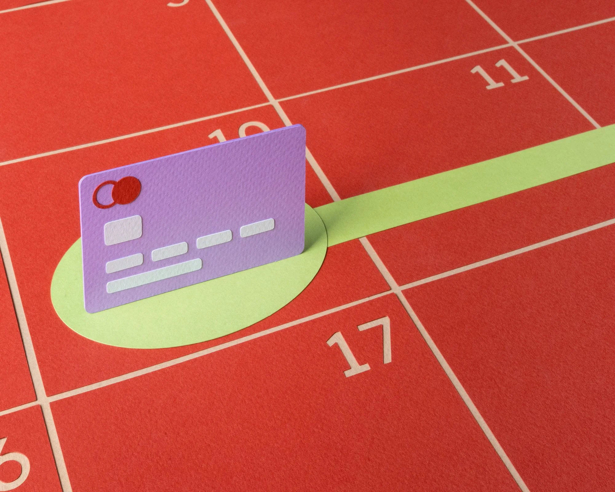 Purple paper credit card upright on zoomed in red calendar