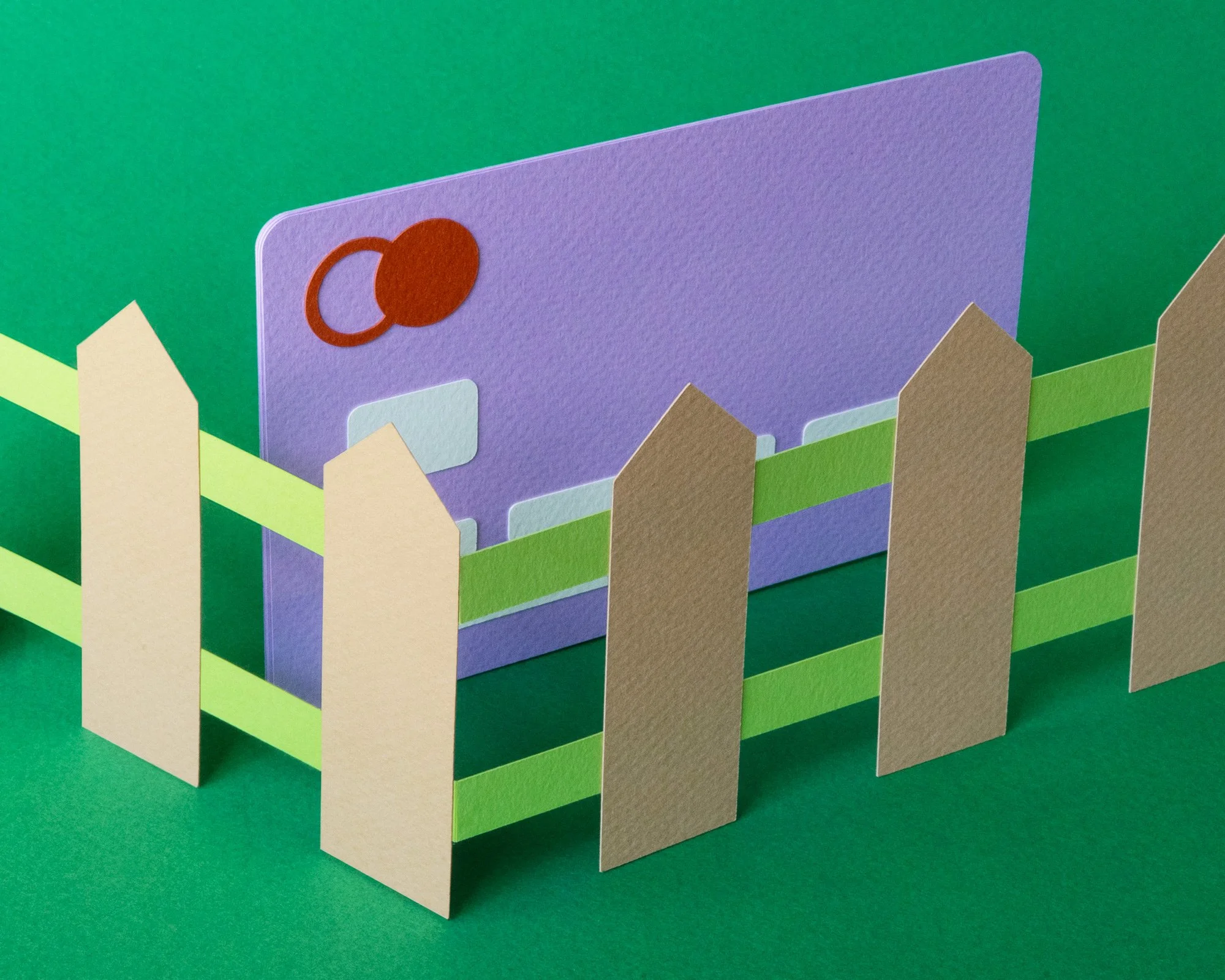 Purple paper credit card on green background surrounded by tan paper fence