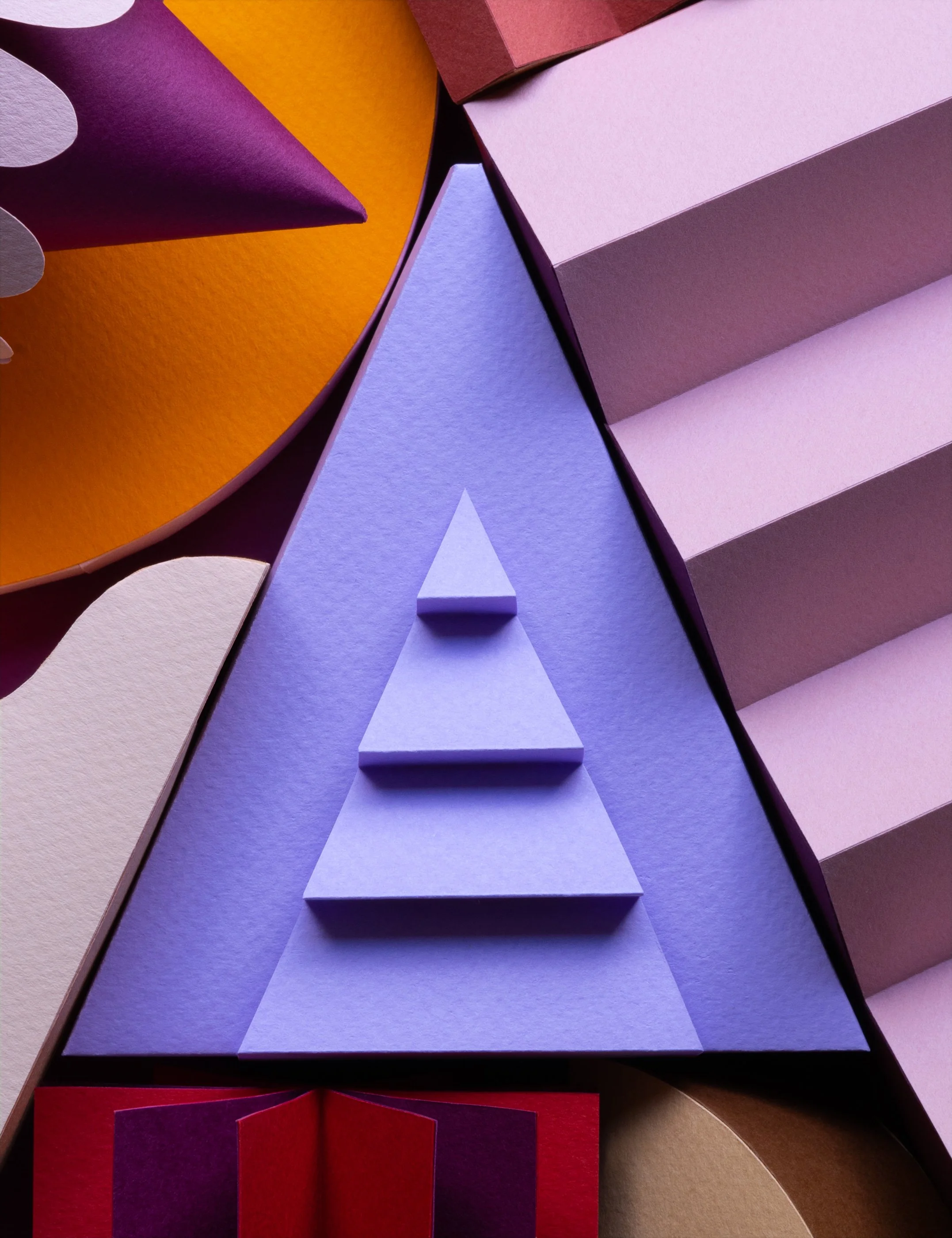 Photograph of colorful paper shapes and textures with a central triangle representing the letter A