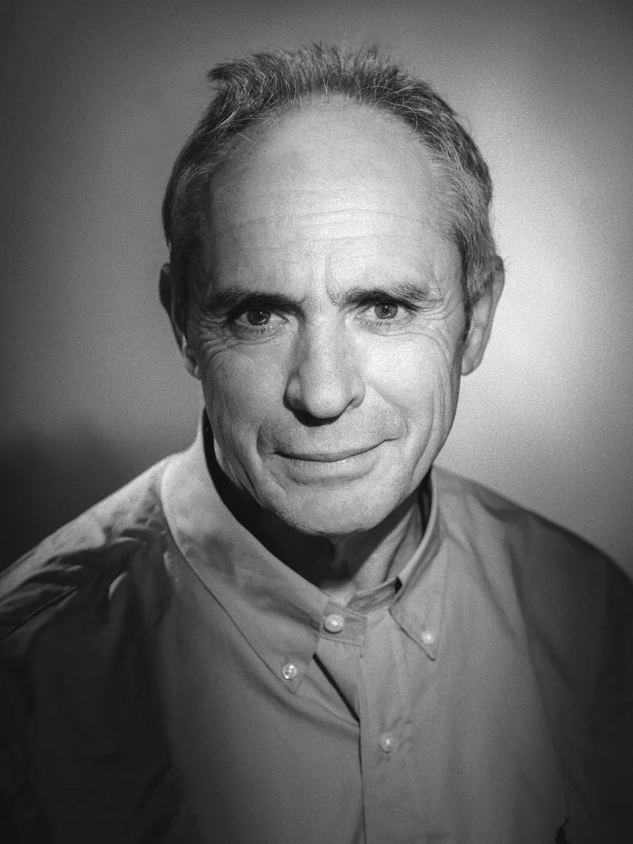 Portrait noir et blanc d'un homme souriant portant une chemise à col bouton.