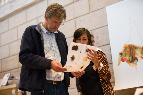 Museum visitors examine Re:depiction map to locate original artworks as described by museum staff.