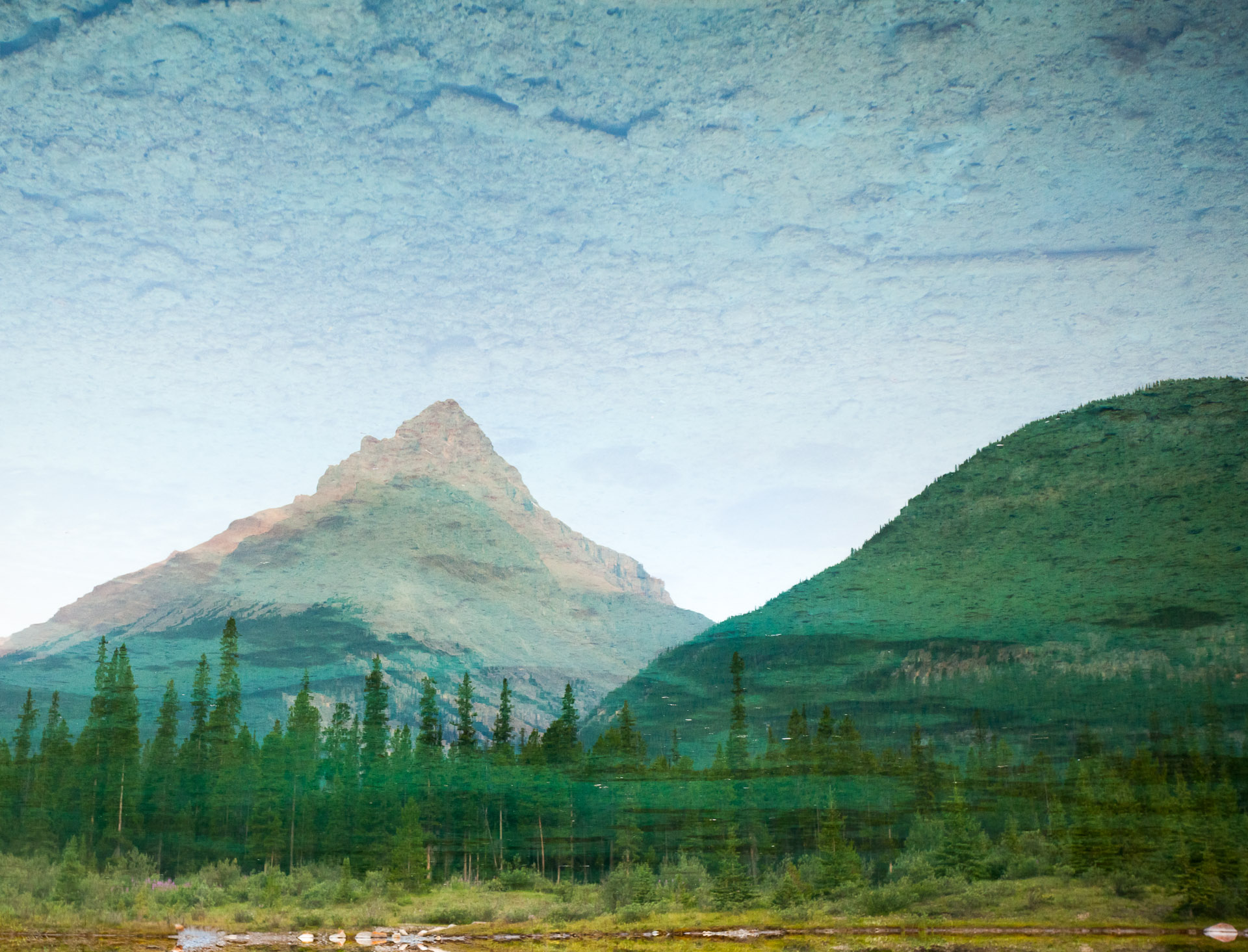 This past summer I visited the Canadian Rockies for the first time and was blown away by their raw magnificence. Here, mountains and forest are reflected in the crystal clear waters of a small lake, creating a surreal landscape view.