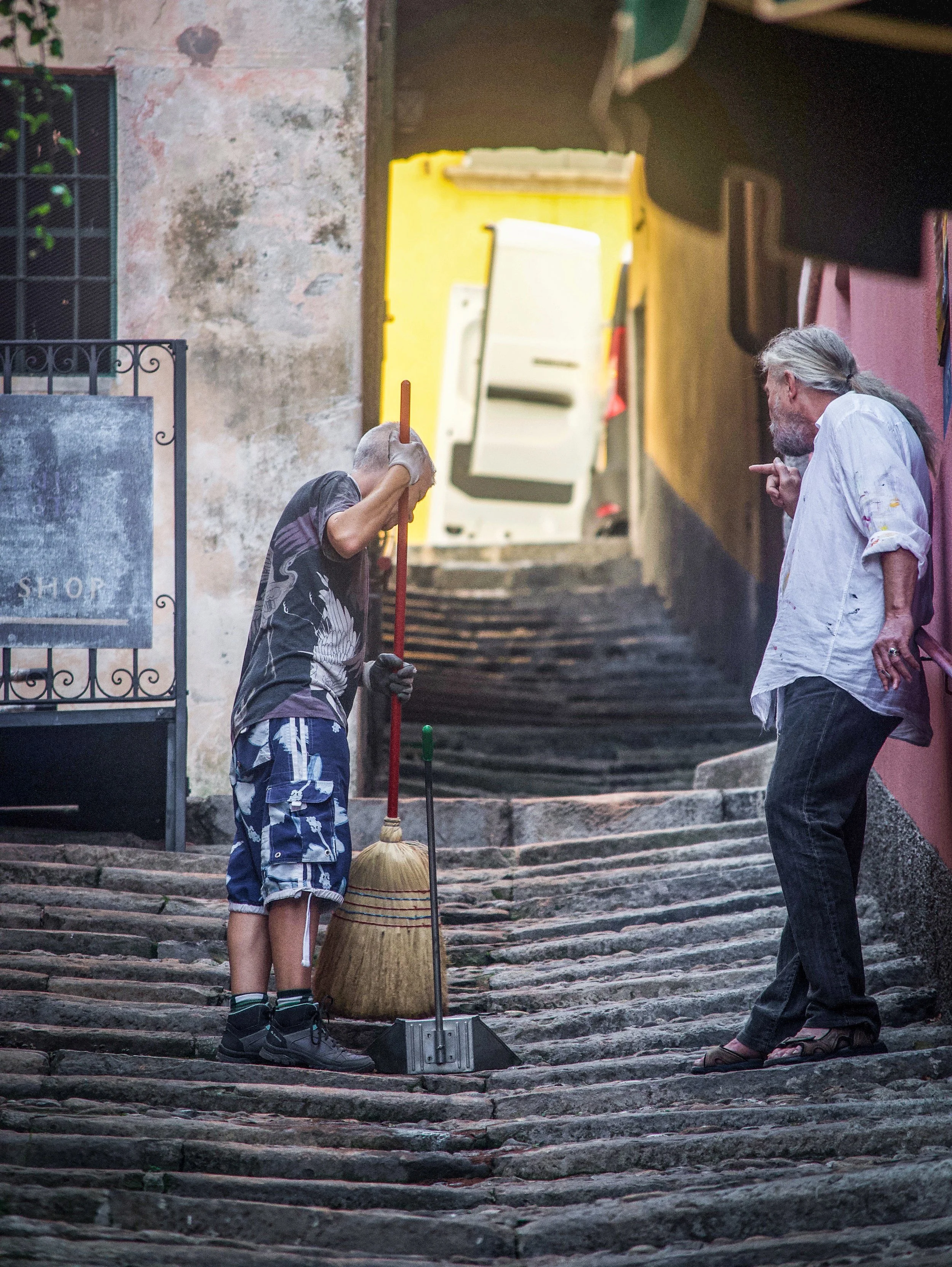  A sweeper and a friend perched on a stone  stairway in Varenna, Italv.  ************************************  (Photo: © 2019 Joseph Kellard/kellardmedia.com 