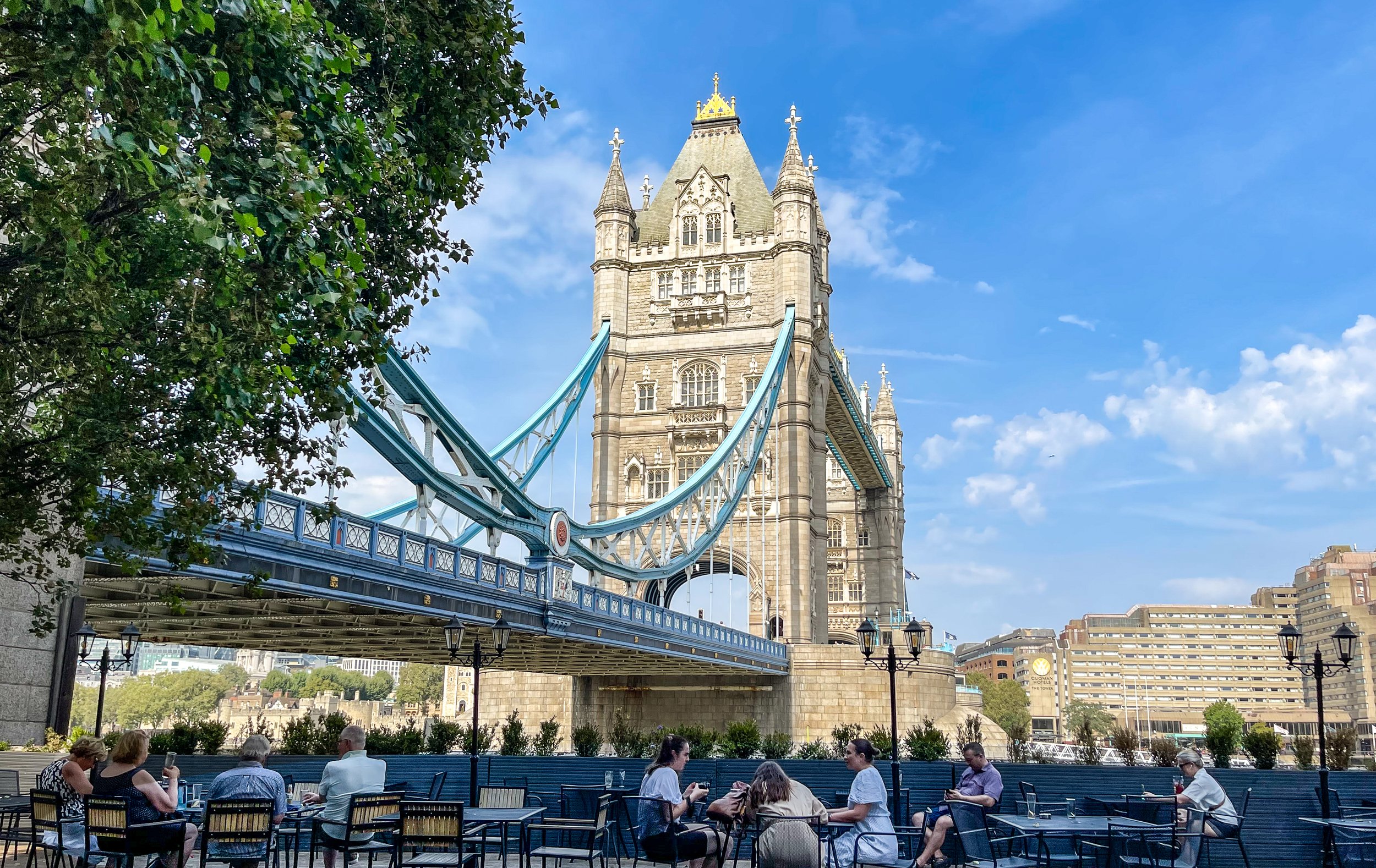 Seated in the shadows of Tower Bridge on the south bank of the Thames River in London. The drawbridge was opened in 1894 and spans 800 feet between its twin towers that rise 200 feet above the water. The towers house the machinery that raises the