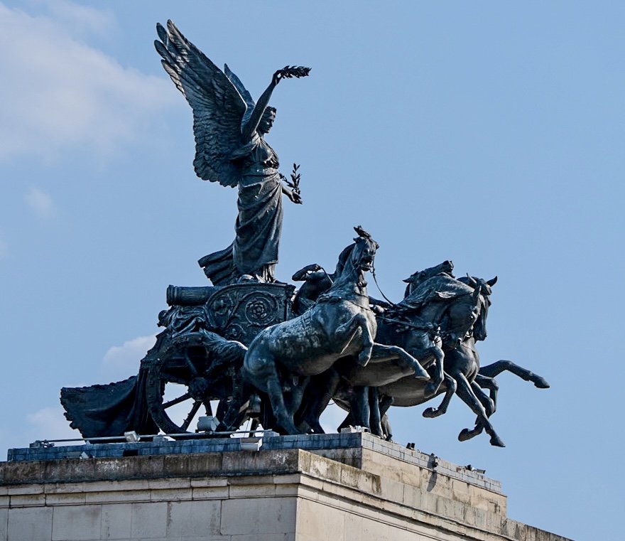 “Peace descending on the Quadriga of War '' – the largest bronze statue in Europe – crowns the Wellington Arch at Hyde Park in London. Created by Adrian Jones, the allegorical sculpture features a four-horse chariot (or quadriga) and Nike, the wing