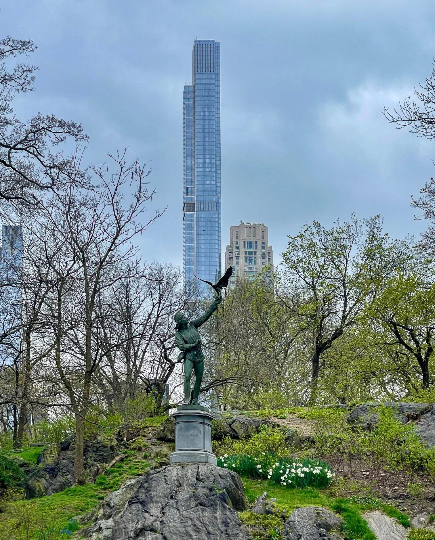  A sculpture’s bird of prey is set to soar into the New York City sky; a skyscraper rises to the clouds.    The Falconer by English sculptor George Blackall Simonds rests on a granite pedestal atop a rocky outcrop along Terrace Drive in Central Park 