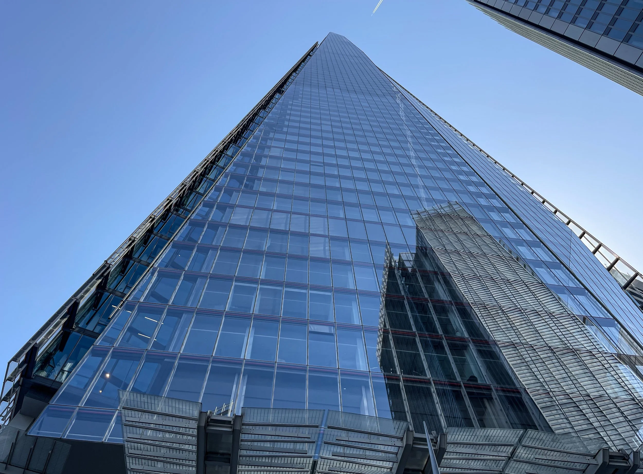  The Shard reflects a neighboring building as an airplane flies overhead. Designed by architect Renzo Piano, the tallest skyscraper in London was constructed between 2009 and 2012. It is 1,020 feet high and houses offices, bars, restaurants and hotel