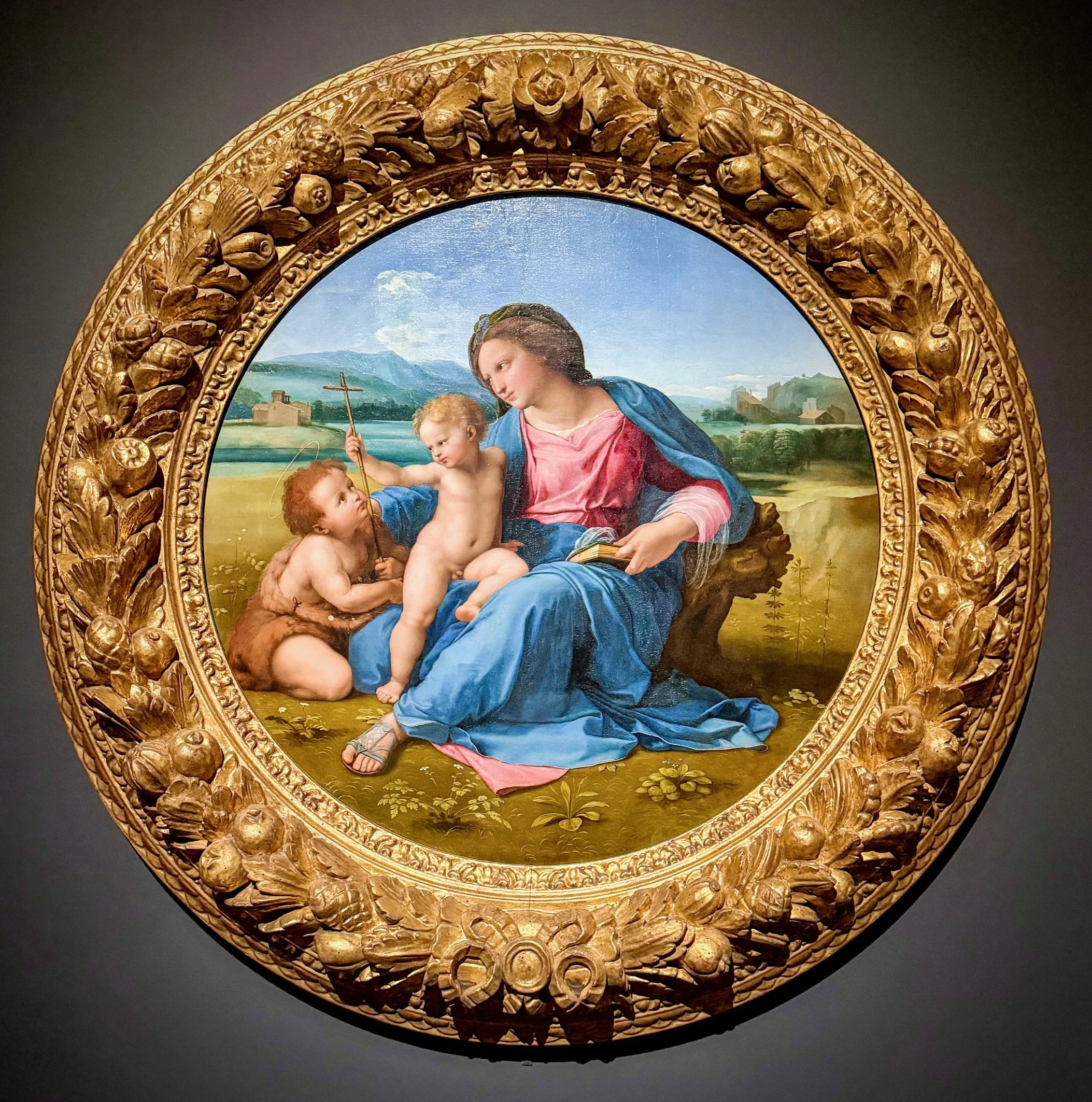  The Virgin and Child with the Infant Saint John the Baptist in a Landscape, otherwise known as The Alba Madonna, was painted by Raphael between 1509 and 1511. The painting’s round format, known as a tondo, was popular among Florentine artists and th