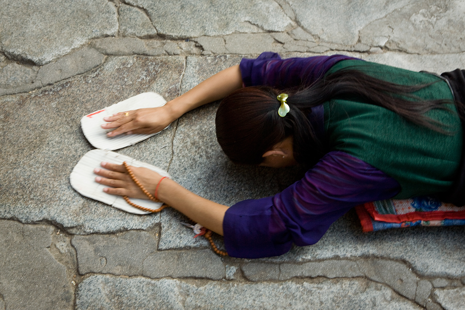 A pilgrim prostrates herself repeatedly in front of the Jokhang, the first Buddhist temple in Tibet, which many considered to be the most sacred and important temple in the country. The devout make pilgrimages to the sacred sites in Lhasa, traveling