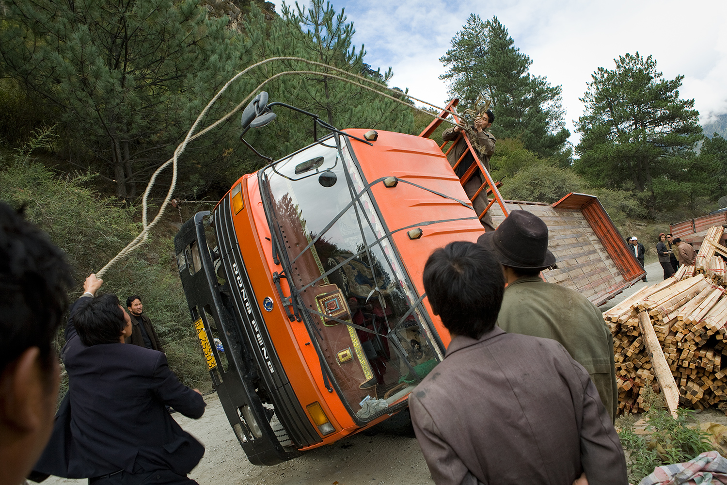  By tying a rope to a tree on the hillside and pulling together, men traveling in a bus helped upturn a truck in remote southeastern Tibet. 