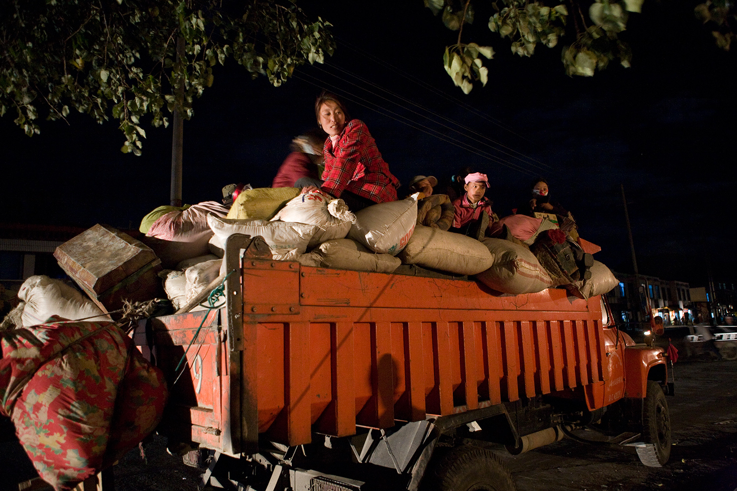  Ready for their journey, a family precariously sits on top of a truck’s cargo in Tsetang. 
