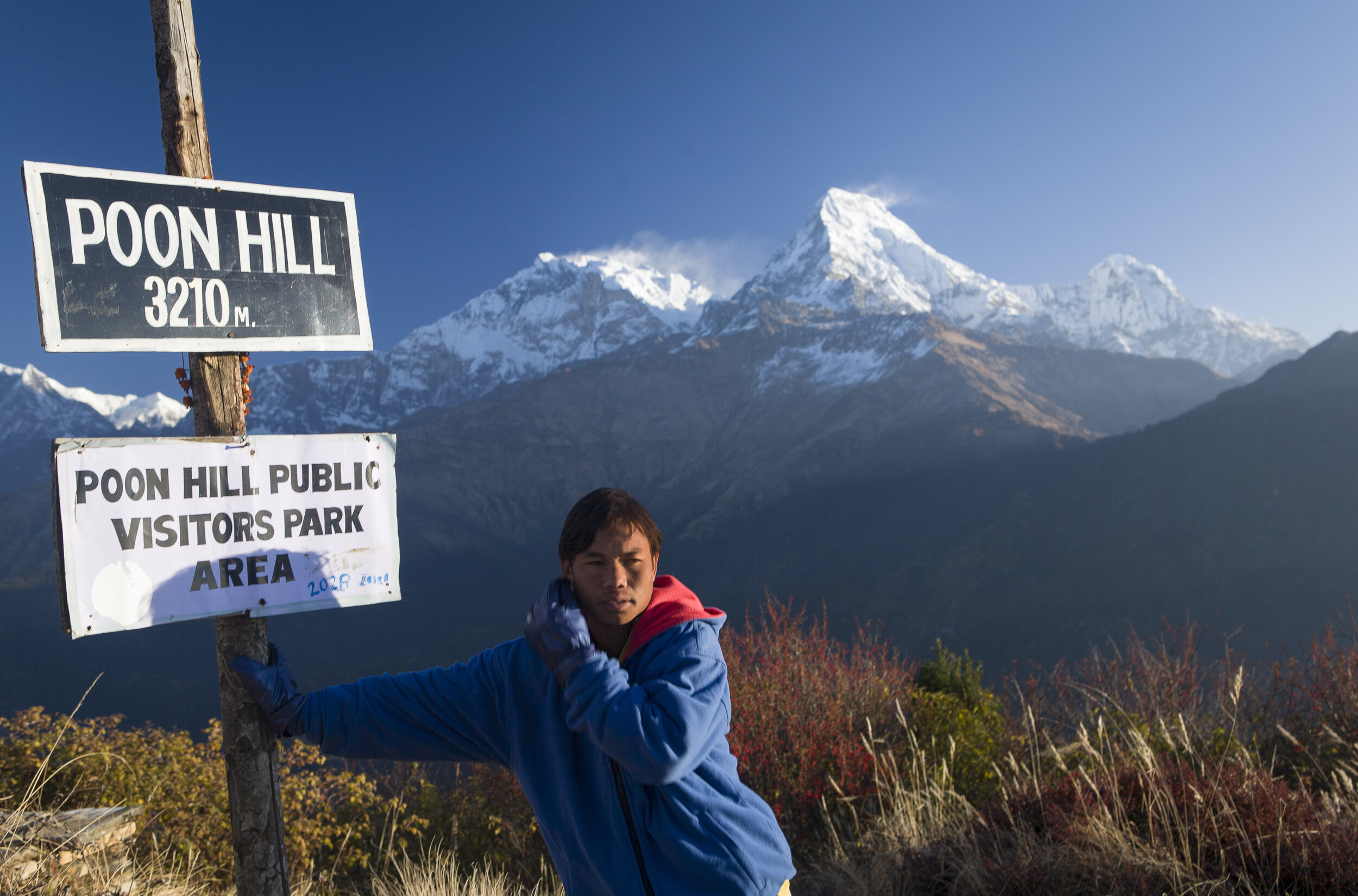  Kumar, a Nepali porter, leans up against a sign on Poon Hill in the early morning.  Annapurna Circuit.  
