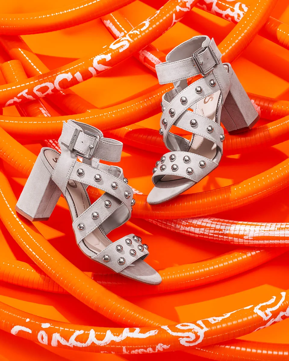 client: circus by sam edelman credits: photo - jenna gang, styling - anna lemi description: gray circus by sam edelman heels resting on orange pipes.