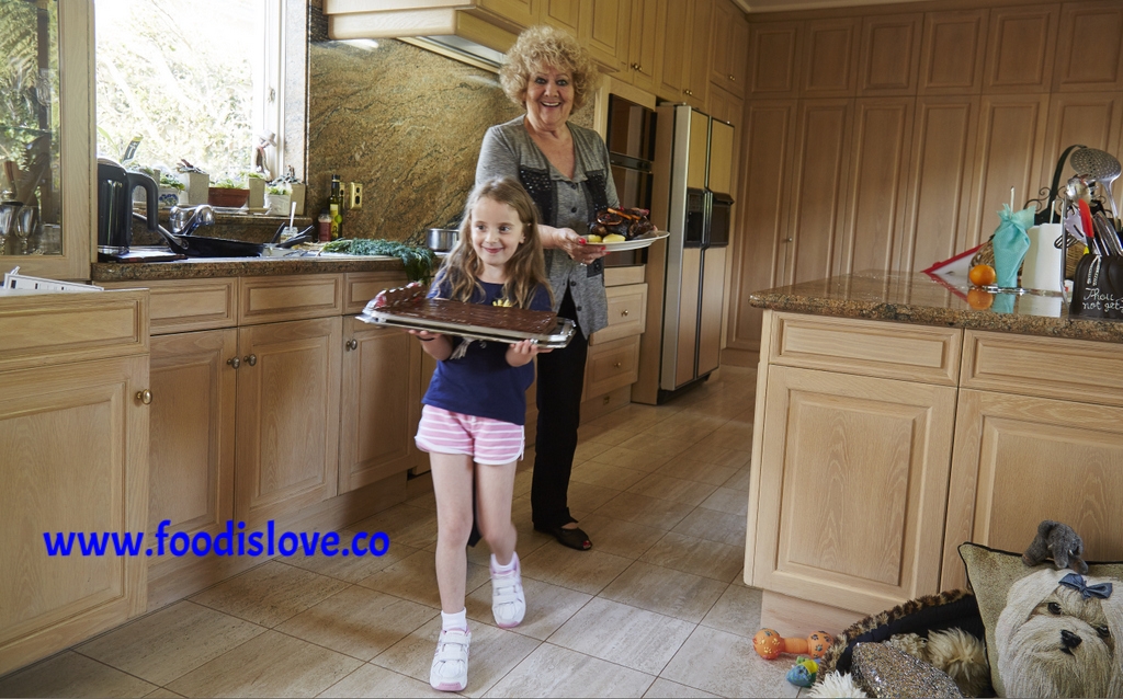 Ruth Scheuer with her grand-daughter Nika carrying the dishes they've prepared in Ruth's kitchen. Nika is very pleased to be in charge of the Nutella wafer cake!