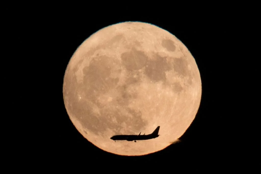 Commercial jet flies across the supermoon this week. (Photo: Ng Hang Guan, AP)