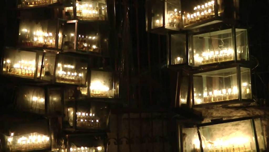 A bank of Hannukah candles, outside a Jerusalem yeshiva. It is the last night of Hannukah, as you can tell because all the seven candles in each glass case have been lit. 