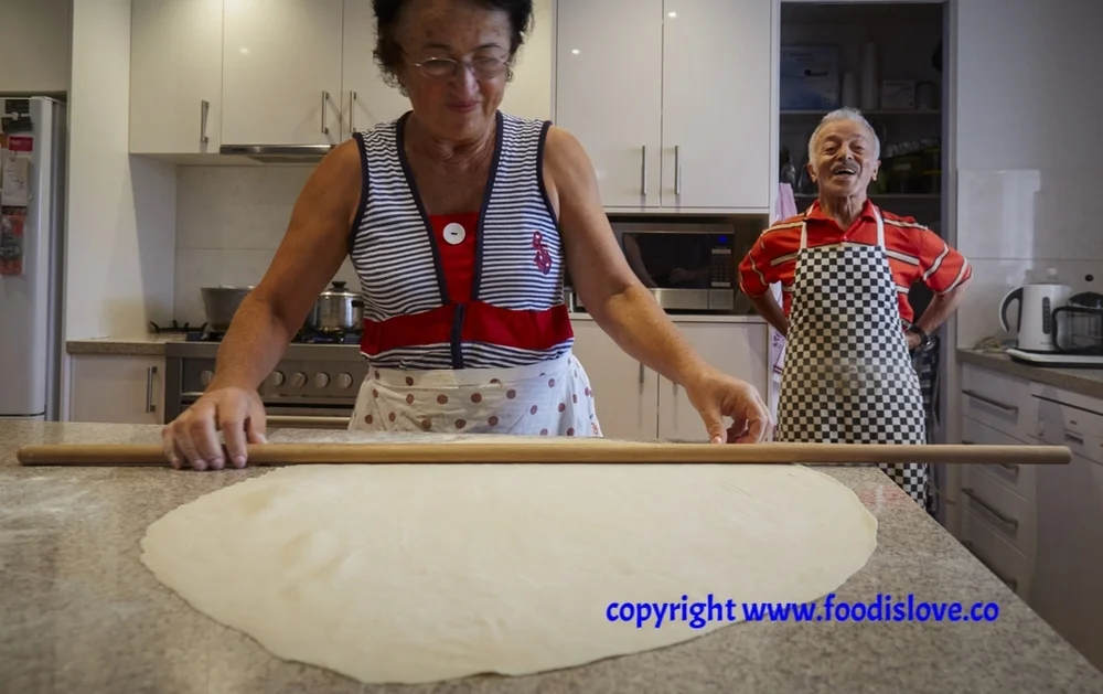 Marta and Ilya Pinhasov. Marta makes dough for Central Asian dumplings, Mantu and Dushpera, using 2 pieces of kitchen equipment, both made of wood - a rolling pin and a curtain rod!