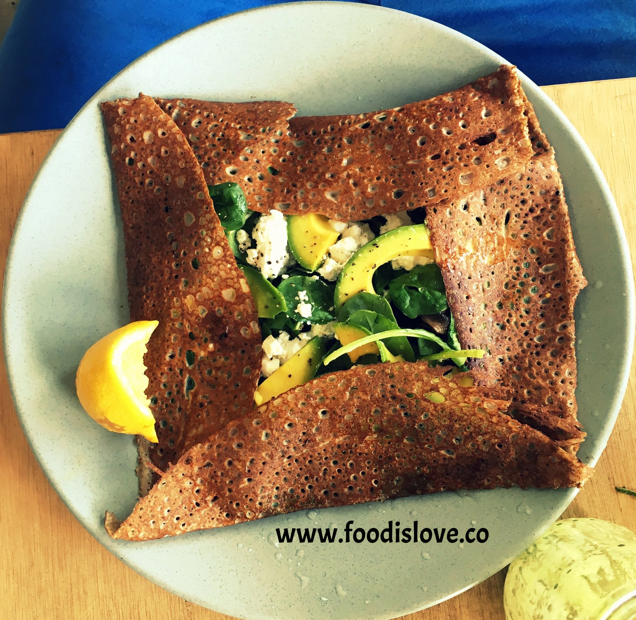 Gluten free buckwheat pancake filled with avocado, greens, feta and field mushrooms