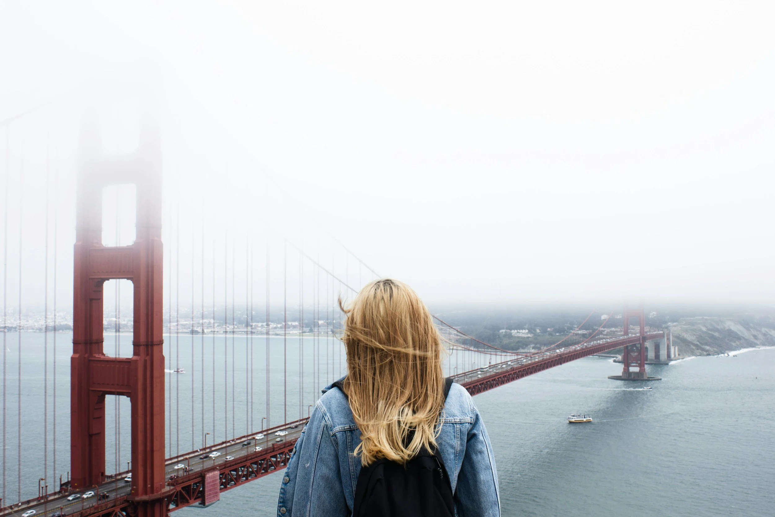 Woman with backpack looking at Golden Gate Bridge