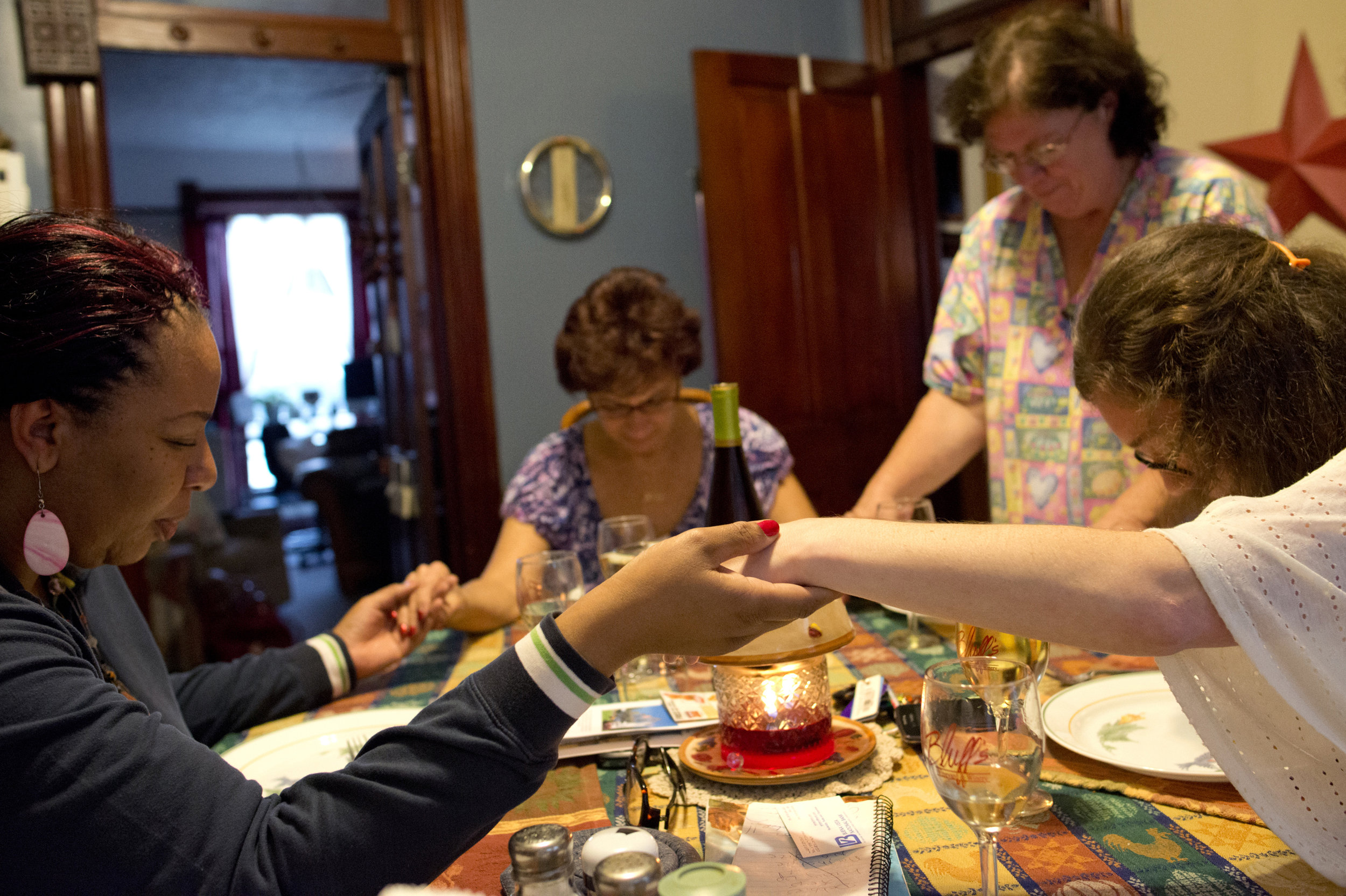 Debra Kennedy, left, Gayle Ayala, middle left, Sheryl Moore, middle right, and Kellie hold hands in prayer before sharing a meal at the Hospitality House. Kellie and Sheryl both have husbands staying at Menard Correctional Center in Chester, Ill.