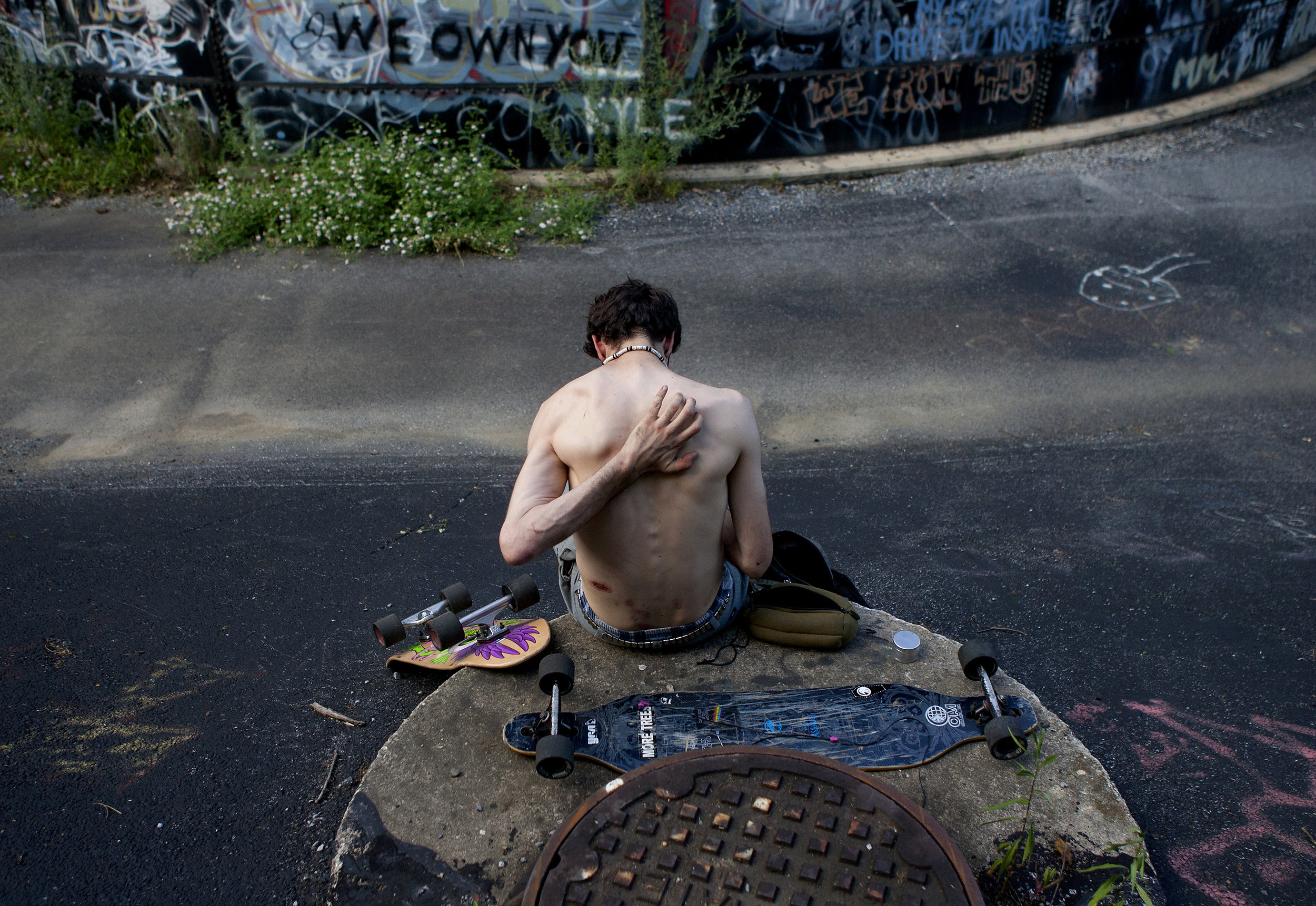Jesse Horsford relaxes at "Super Blue" during a skate trip. The skaters referred to the site as a secret, but it is actually a closed municipal landfill located in a fenced in wooded area that they have to trespass into in Harrisburg, Penn. 
