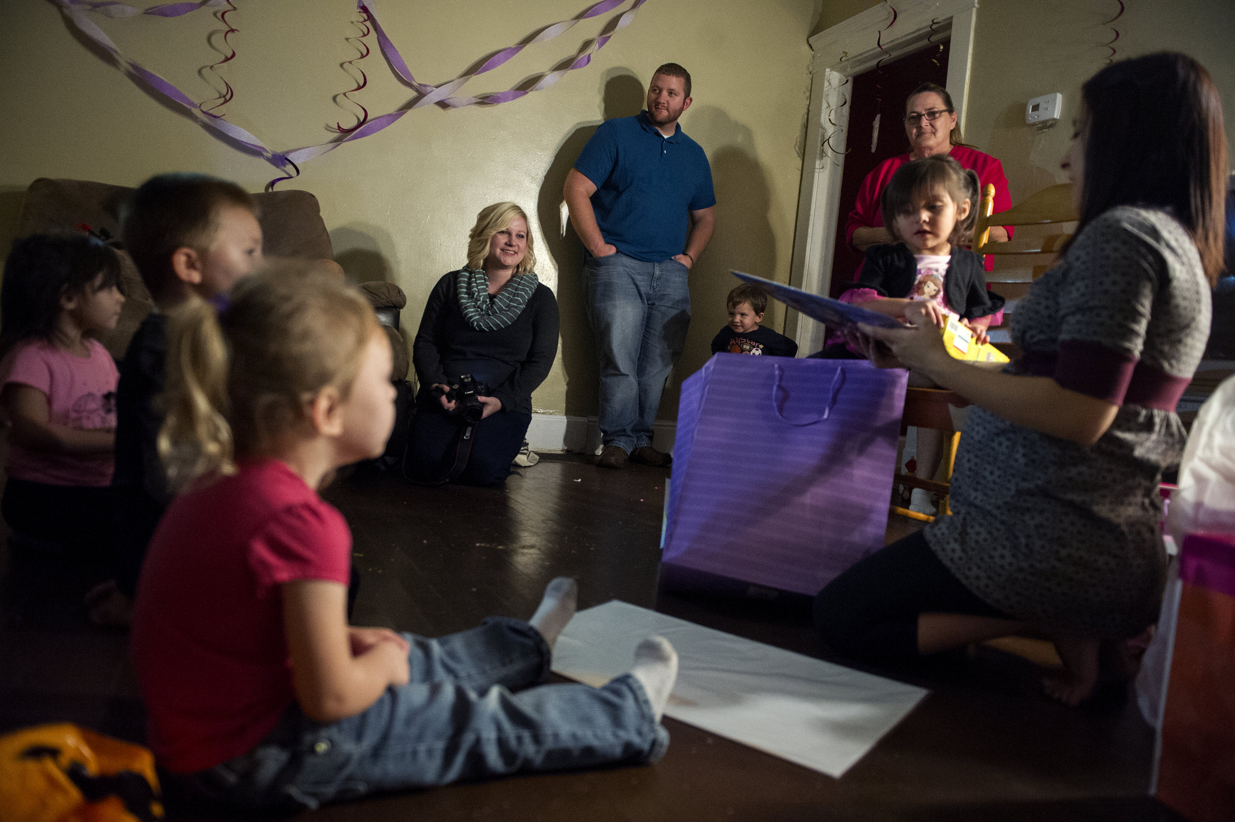  Erickia Wilson (center left) and her husband Michael Wilson (center right) watch as Angelica, the birthmother of the child they will adopt, helps her daughter Prisilla, 3, open presents at her birthday party at Angelica's home in Evansville Friday O