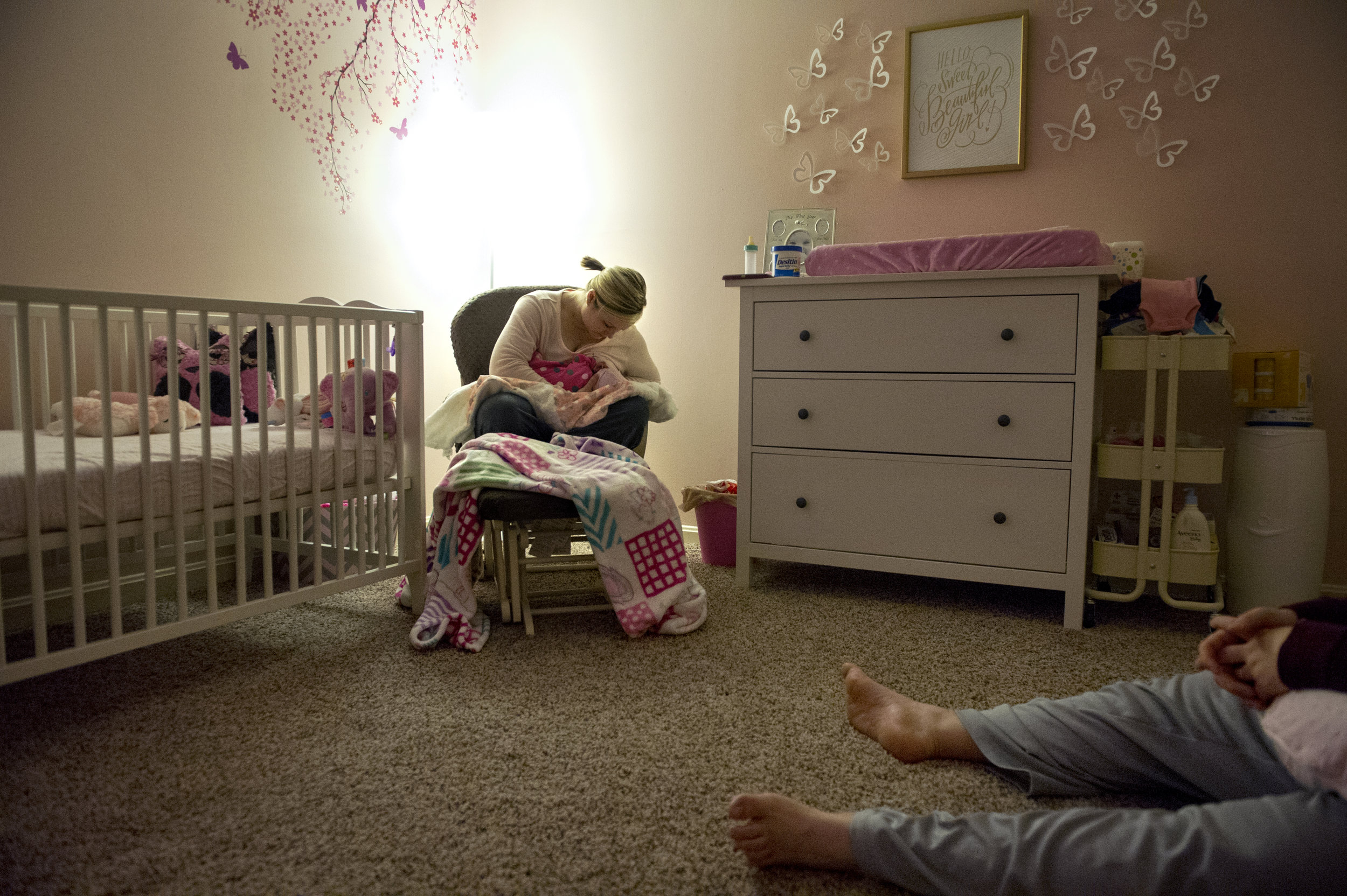  Erickia breast feeds Gracelyn while Michael sits on the floor and wakes himself up after a night of taking turns tending to the newborn at their home in Evansville Thursday Dec. 11, 2014. Over the past seven years Erickia's has physically sacrificed