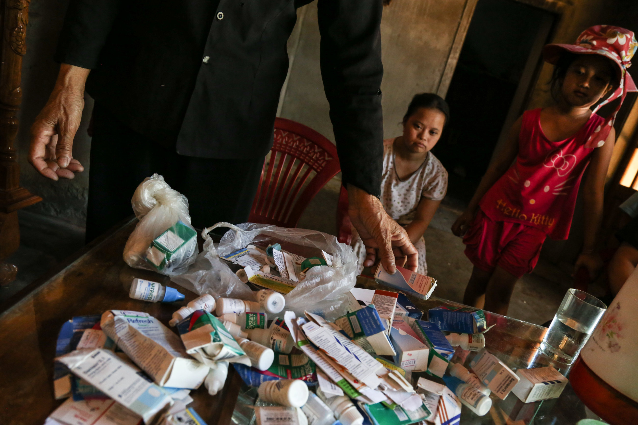 Duong Thi An shows the different medicines her children have to take to survive on a daily basis, some of them already expired. July 28th, 2015.