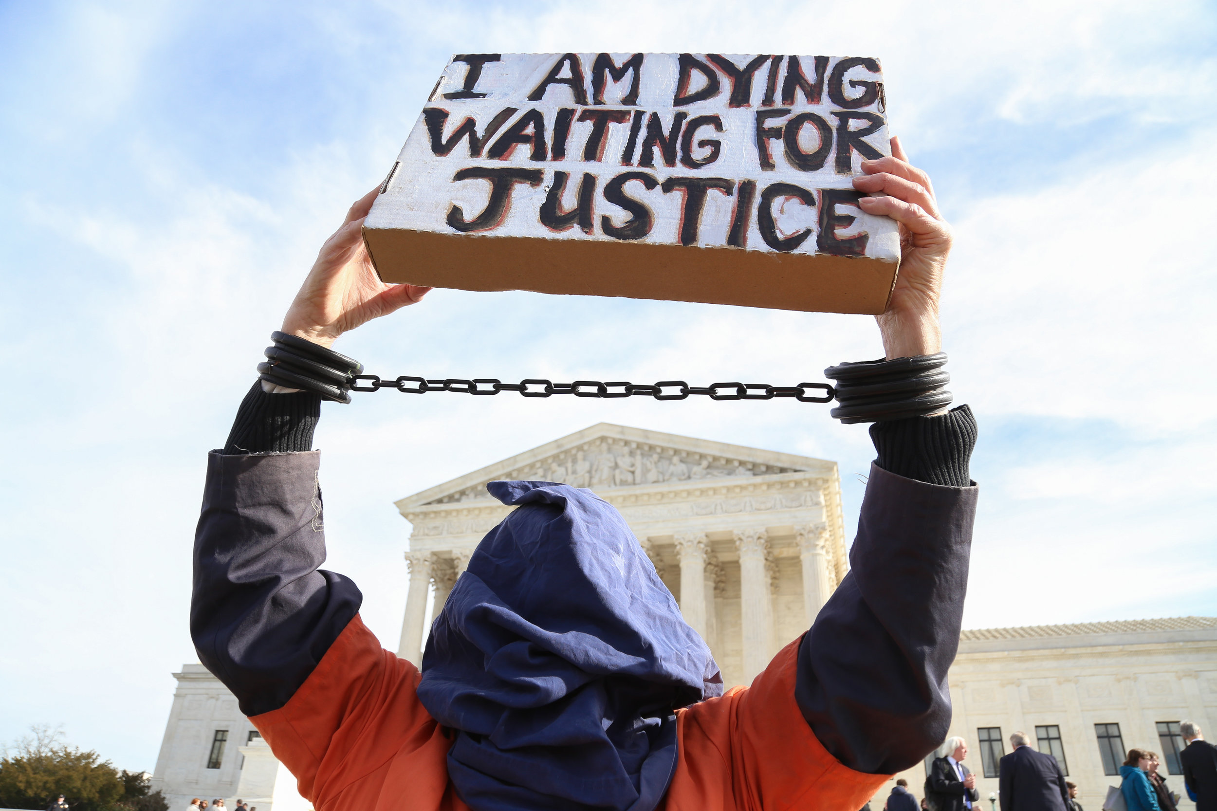 A member of Amnesty International dressed as a Gitmo prisoner holds a sign in front of the Supreme Court stating 'I am dying waiting for justice'. -Jan 11th, 2017.