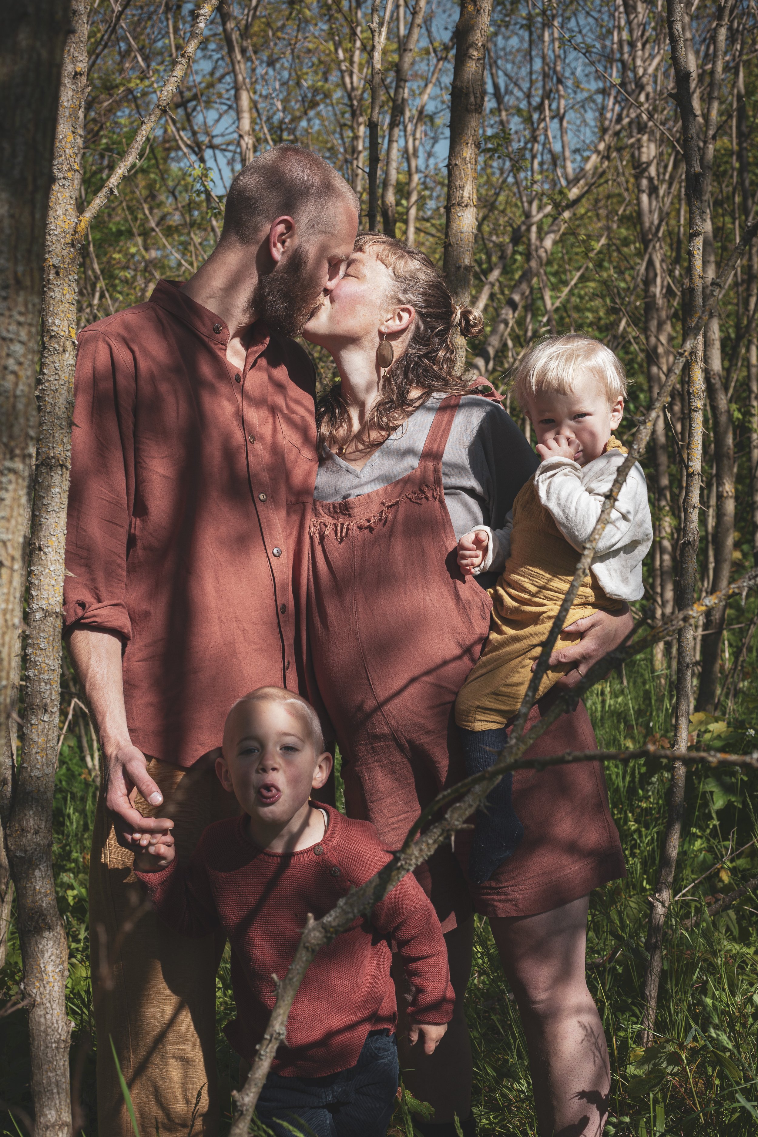 Familie beim Fotoshooting im Wald, Küsse, spielen, Kinder und Erwachsene, Familienportrait, Natur. 