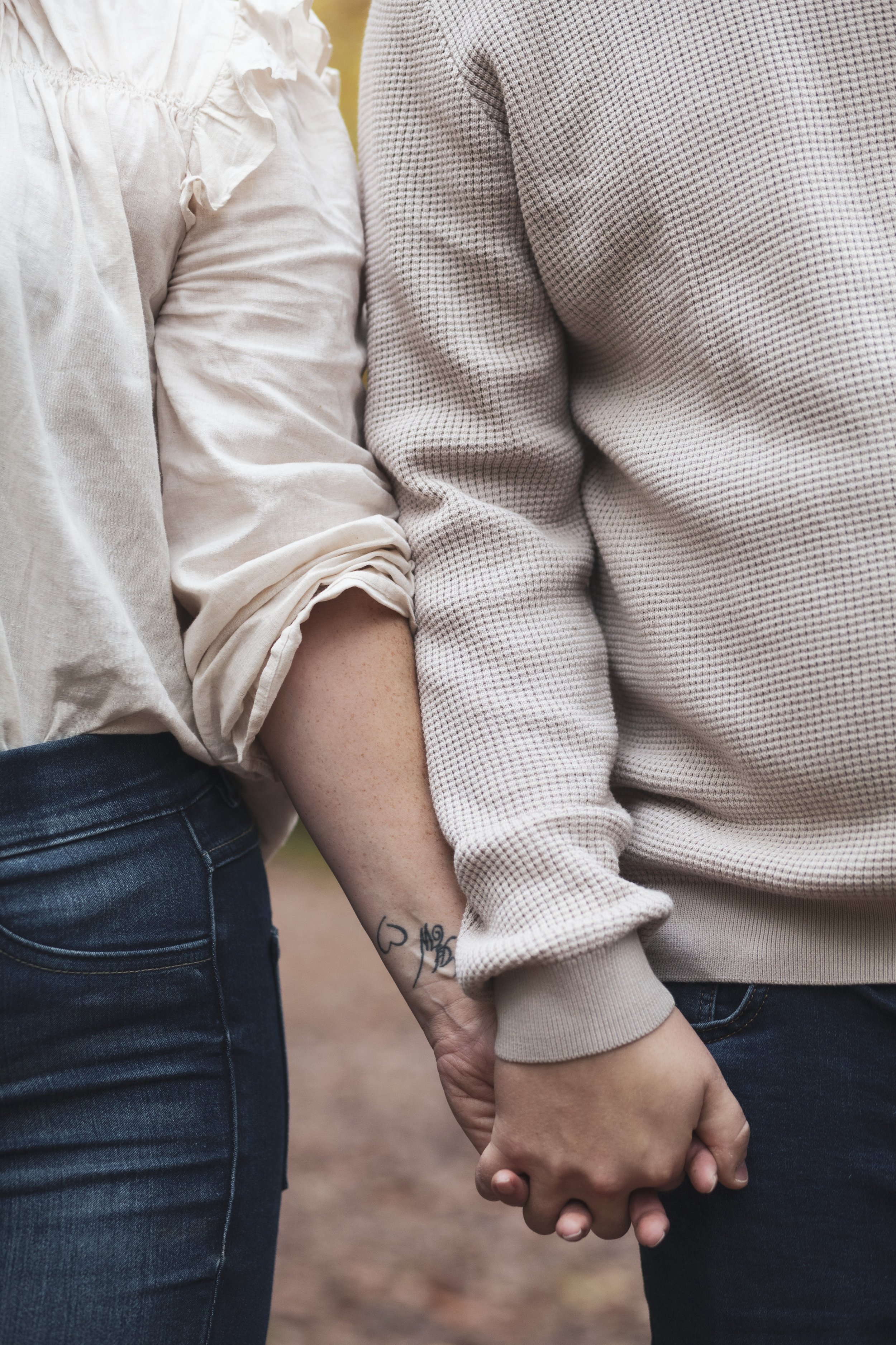 Zwei Personen, die sich die Hände halten, Nahaufnahme, Freizeitkleidung, im Hintergrund unscharf, couple photoshoot, Pärchenfotografie, Portraitfotografie.