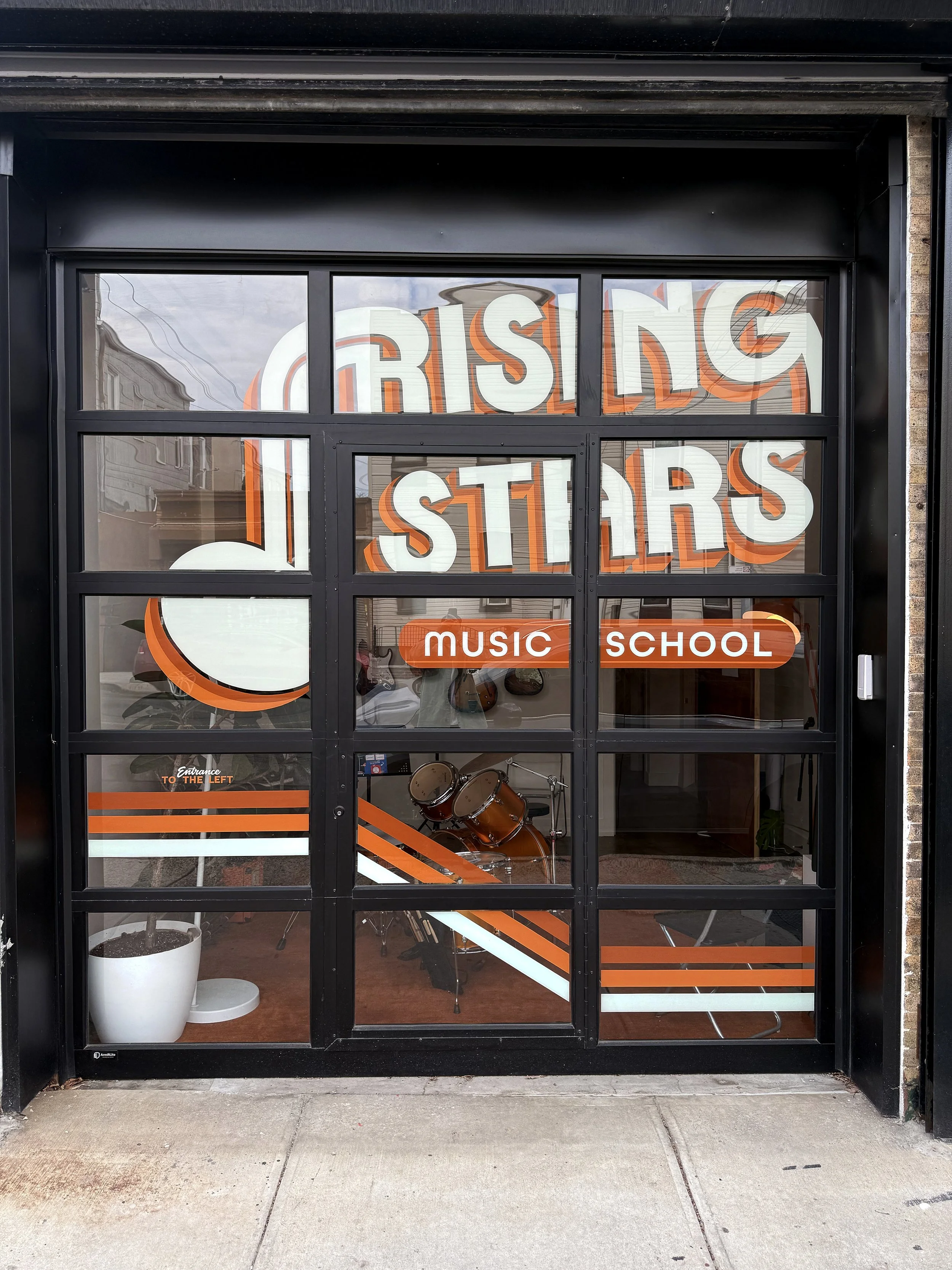 Hand painted sign on storefront windows for Rising Stars Music School in Ridgewood neighborhood of Queens, NY.