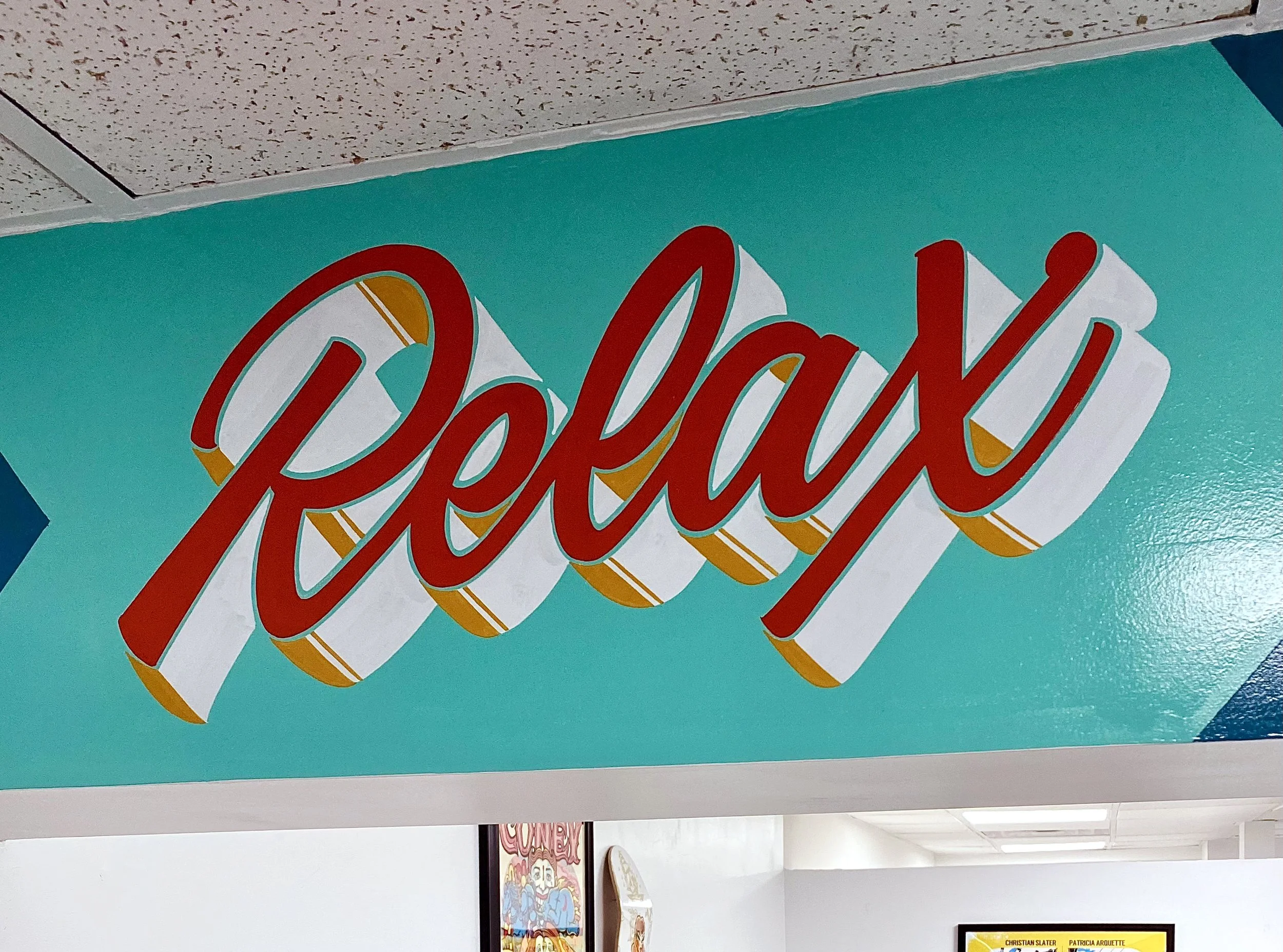 Detail of hand painted "Relax" in script lettering on an interior wall sign