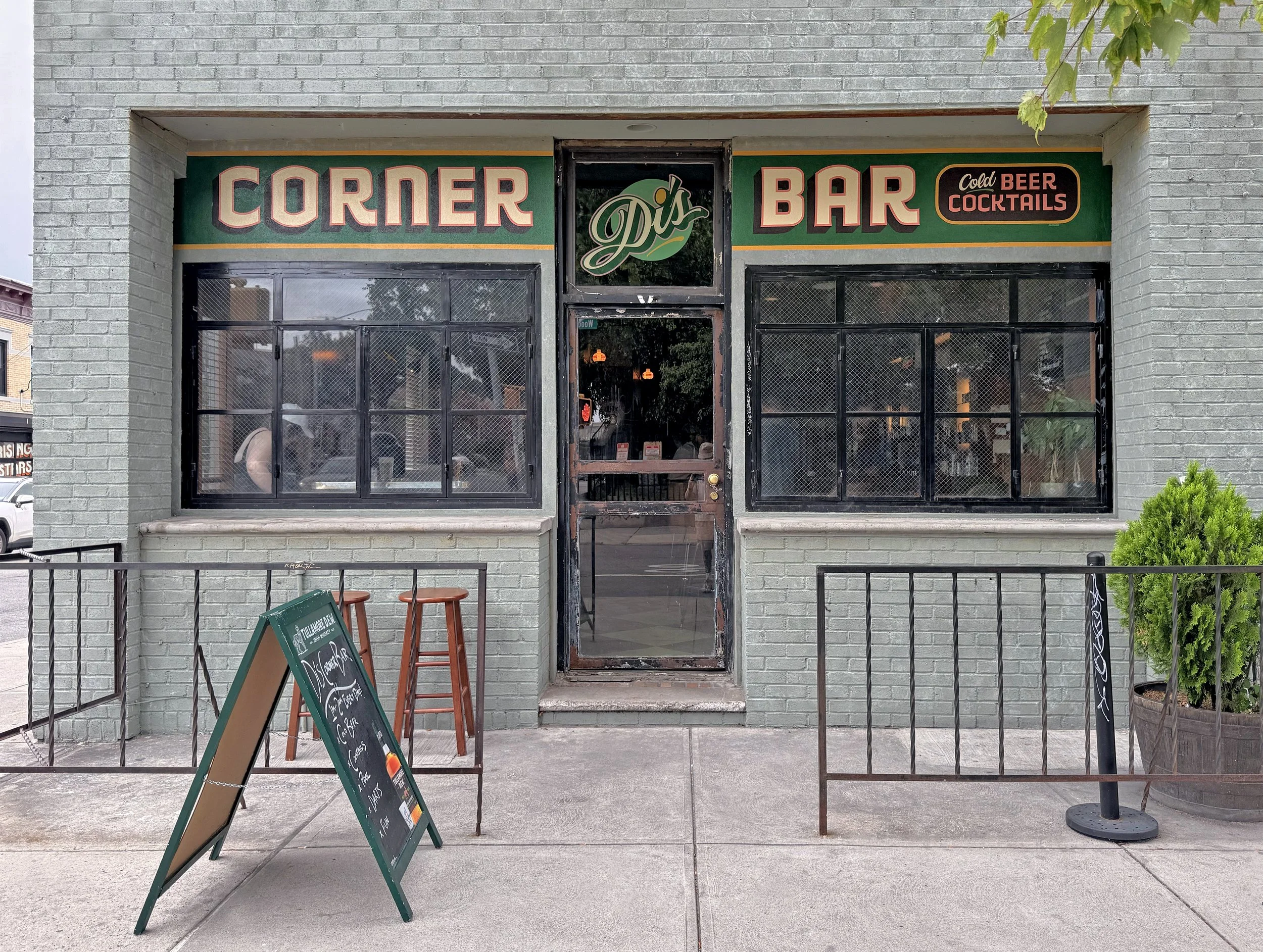Hand painted sign on wall facade for NYC bar and window with script style logo and bold lettering.