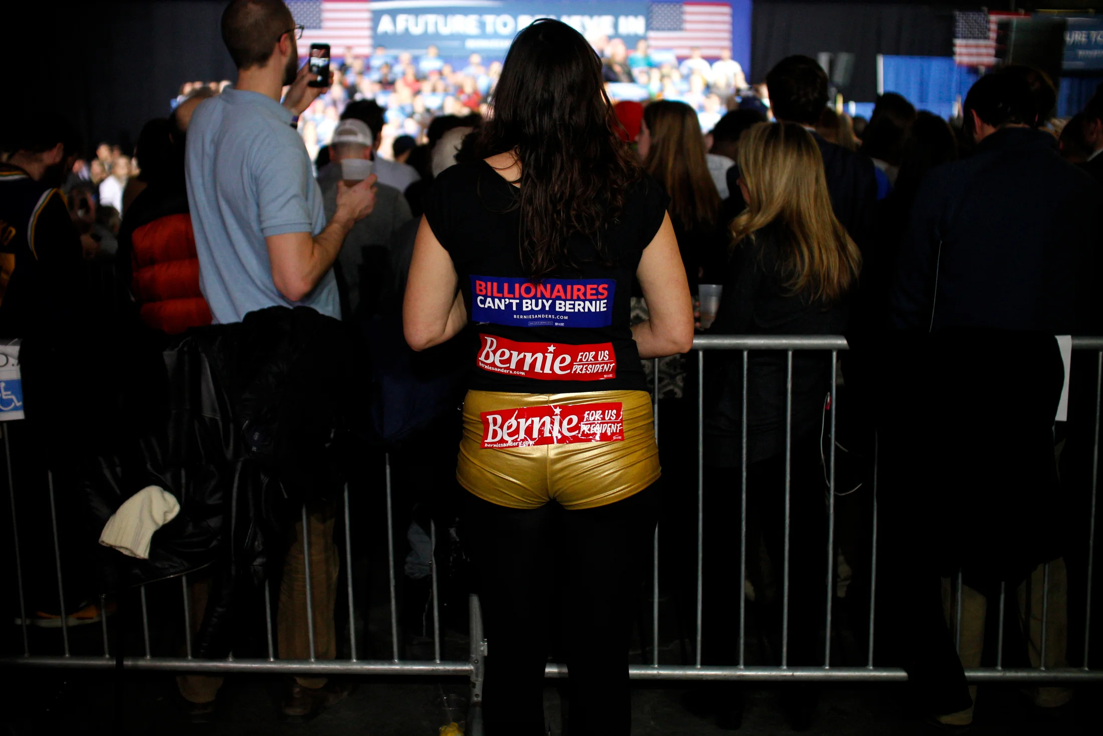 A supporter of Democratic presidential candidate Bernie Sanders watches from the back of the room as the candidate addresses the crowd at a Super Tuesday rally at the Champlain Valley Exposition in Essex Junction, Vermont on March 1, 2016.