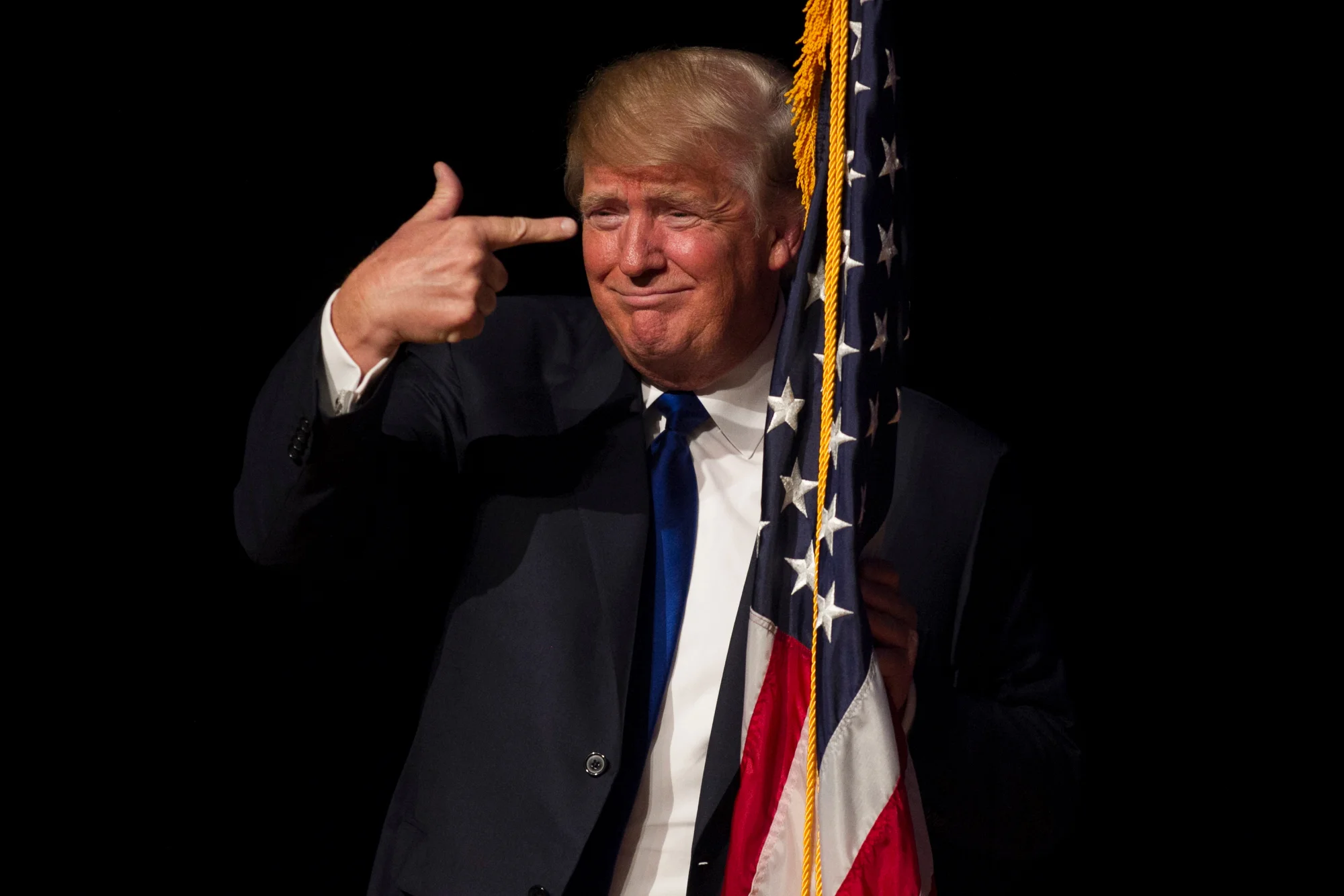 Republican presidential candidate Donald Trump points to an American flag as he walks on stage for a town hall meeting at Pinkerton Academy in Derry, New Hampshire on August 19, 2015.