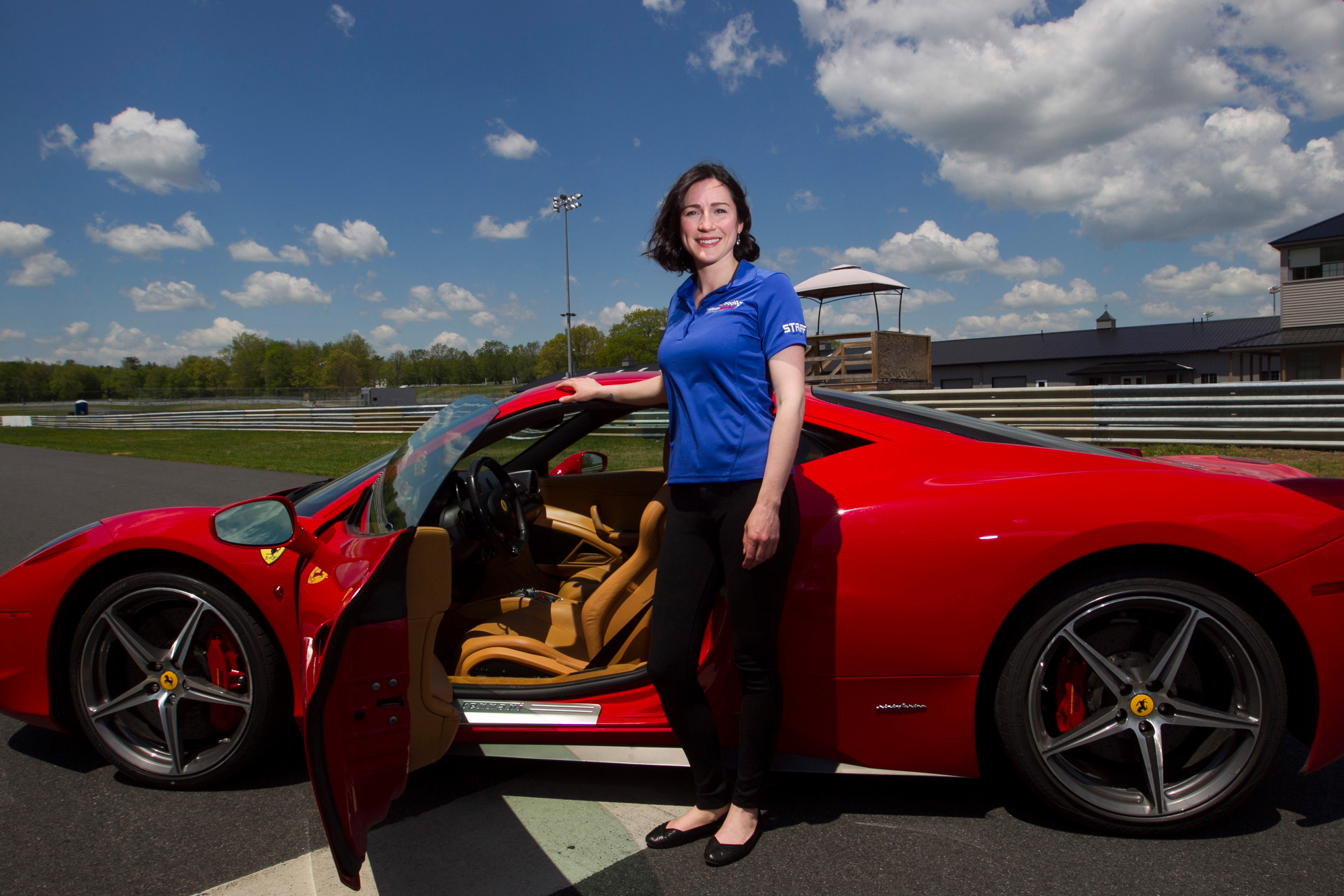 Race car driver Theresa Condict poses for a photo on the track at the Thompson Speedway with a 2012 Ferrari 458 Italia in Thompson, Connecticut on May 23, 2016. Condict competes in the Sports Car Club of America Improved Touring R class and also works at the Speedway which uses the Ferrari for it's exotic car experience.
