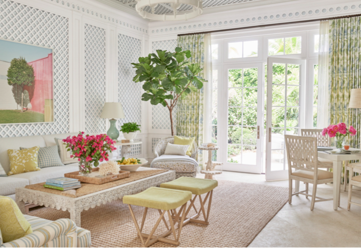 Classic Palm Beach decorative elements in the living room include trellis lined walls, sisal rug, bamboo and wicker furniture in a green, pink and white color palette reminiscent of Lilly Pullitzer