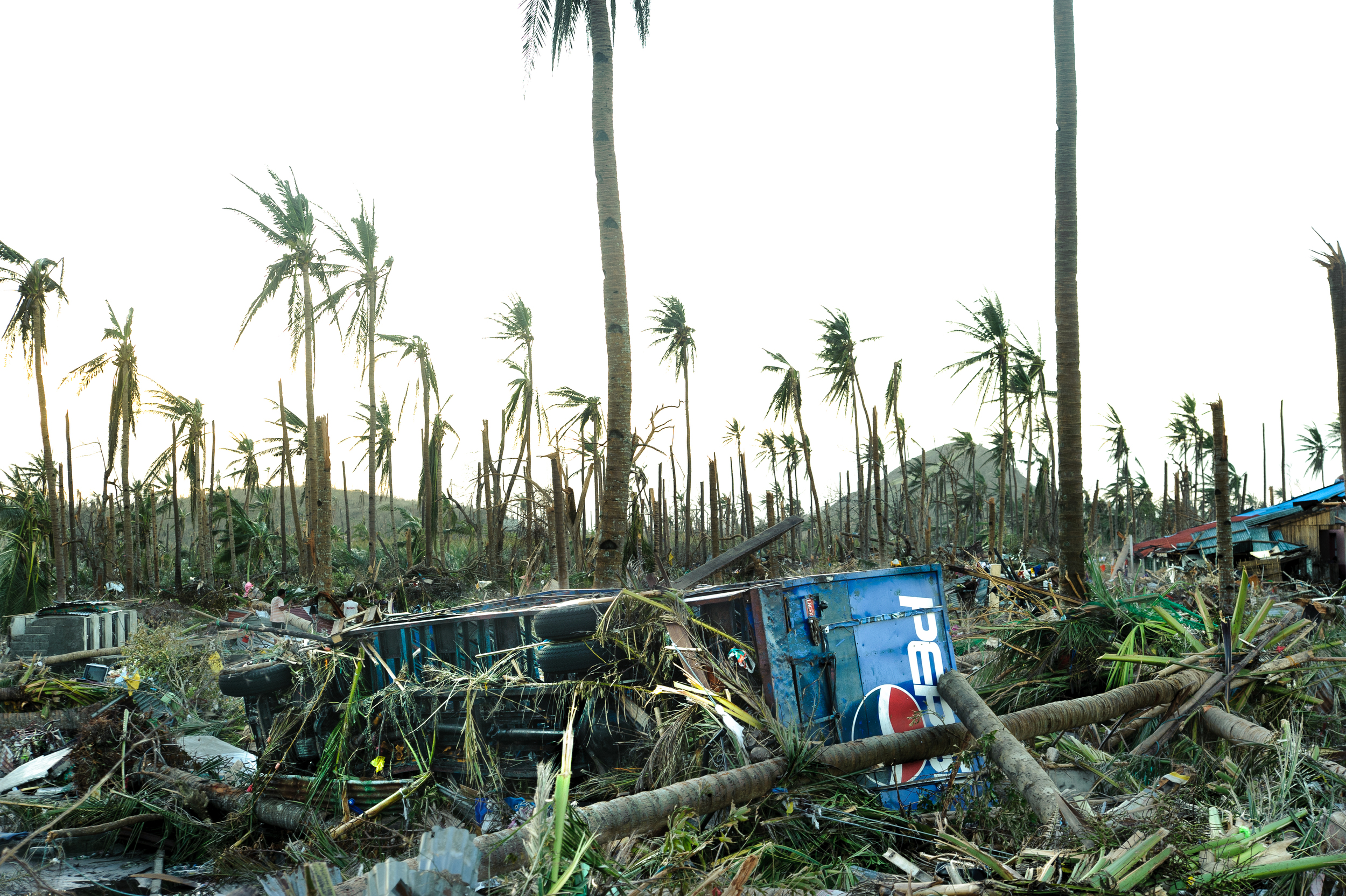 On the road into Tanauan, a Pepsi truck lies overturned. A day later and still without food or fresh water, local residents enter the truck to find crates of unopened Pepsi bottles, which they share amongst the local population and the medical team.
