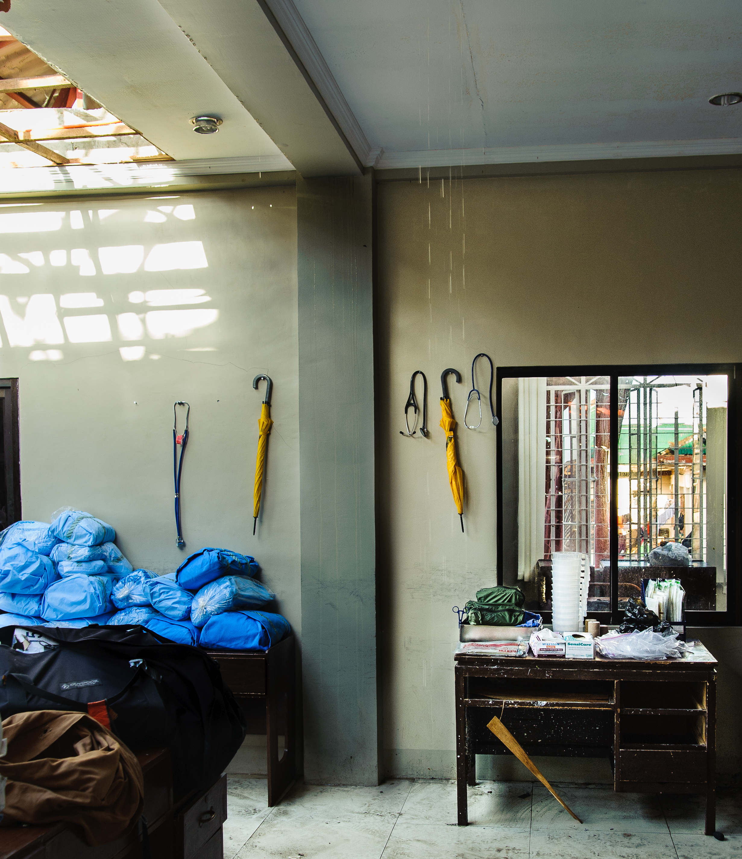Water pours down the walls and through the roof of the team's makeshift OR, where stethoscopes and umbrellas share equal prominence in the care of patients. 