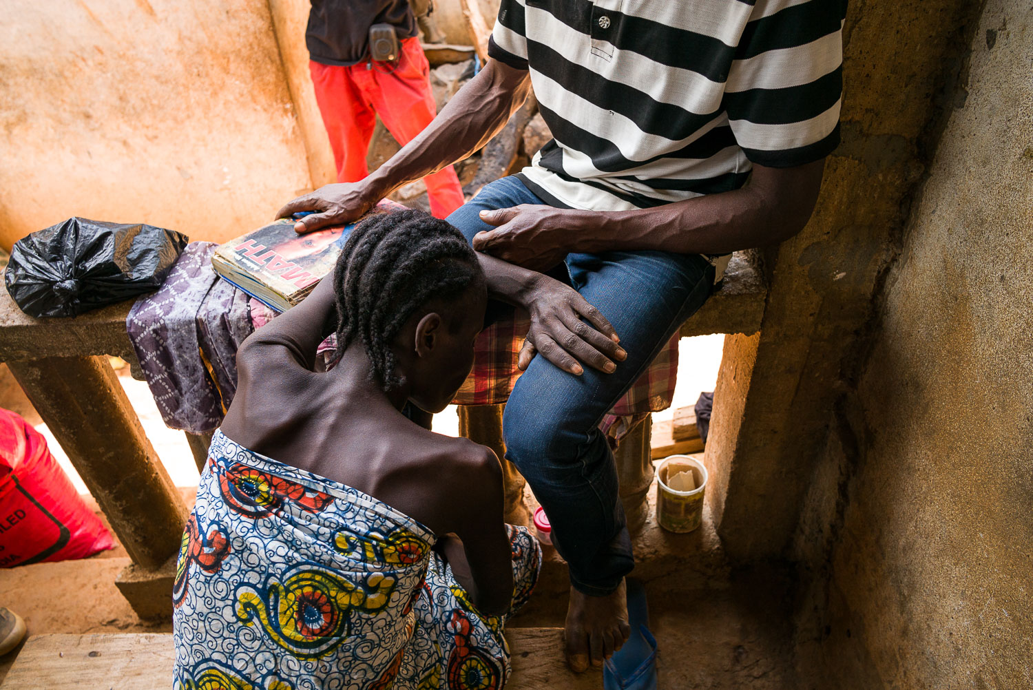 April 2017. Eye Gbakie rests her head on her husband Michael's lap, exhausted and in pain after a rare visit to the doctor. For this particular visit, Matthew had saved up money for weeks, to get a chest xray that had been recommended by the local c