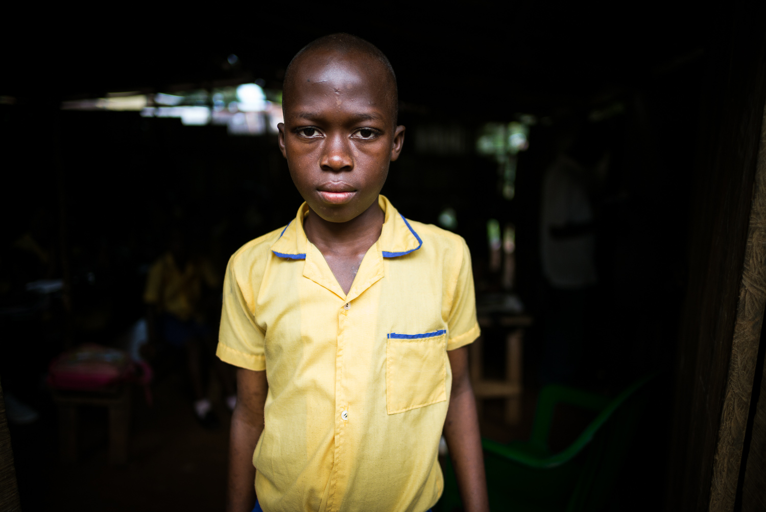 November 2015. 12 year old Francis Yorpoi stands in front of his classroom at the We Yone school in the community of George Brook, in Freetown, Sierra Leone. After the death of his parents, Francis was forced to leave the private school he had atten
