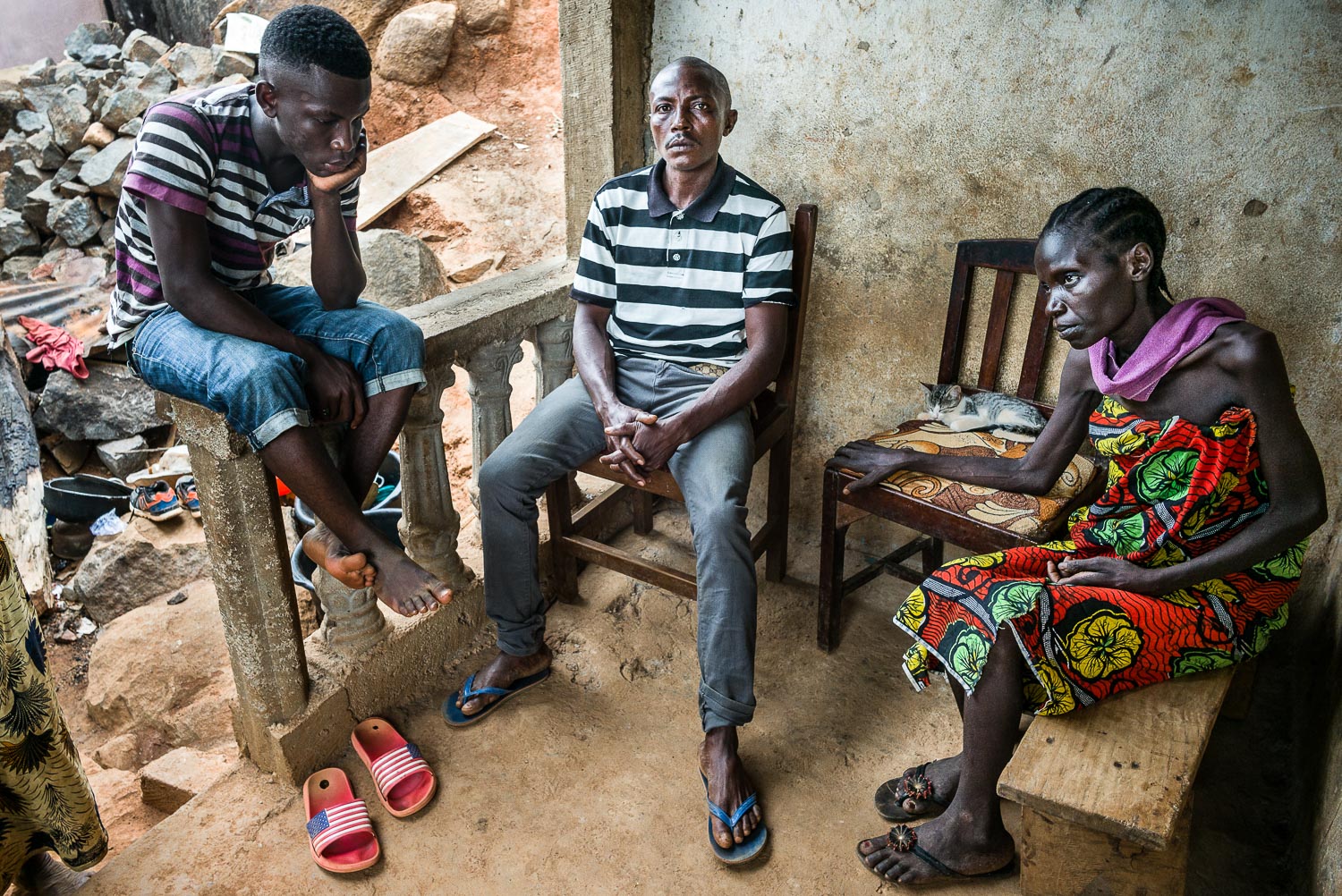 April 2017. Earnest, the eldest son of Matthew and Eye, sits with his parents on the family's front porch. A hub of family activity in 2015, the porch has evolved into something more static. Family members are loathe to leave Eye alone, as she needs help with even the smallest of activities, including sitting and standing.