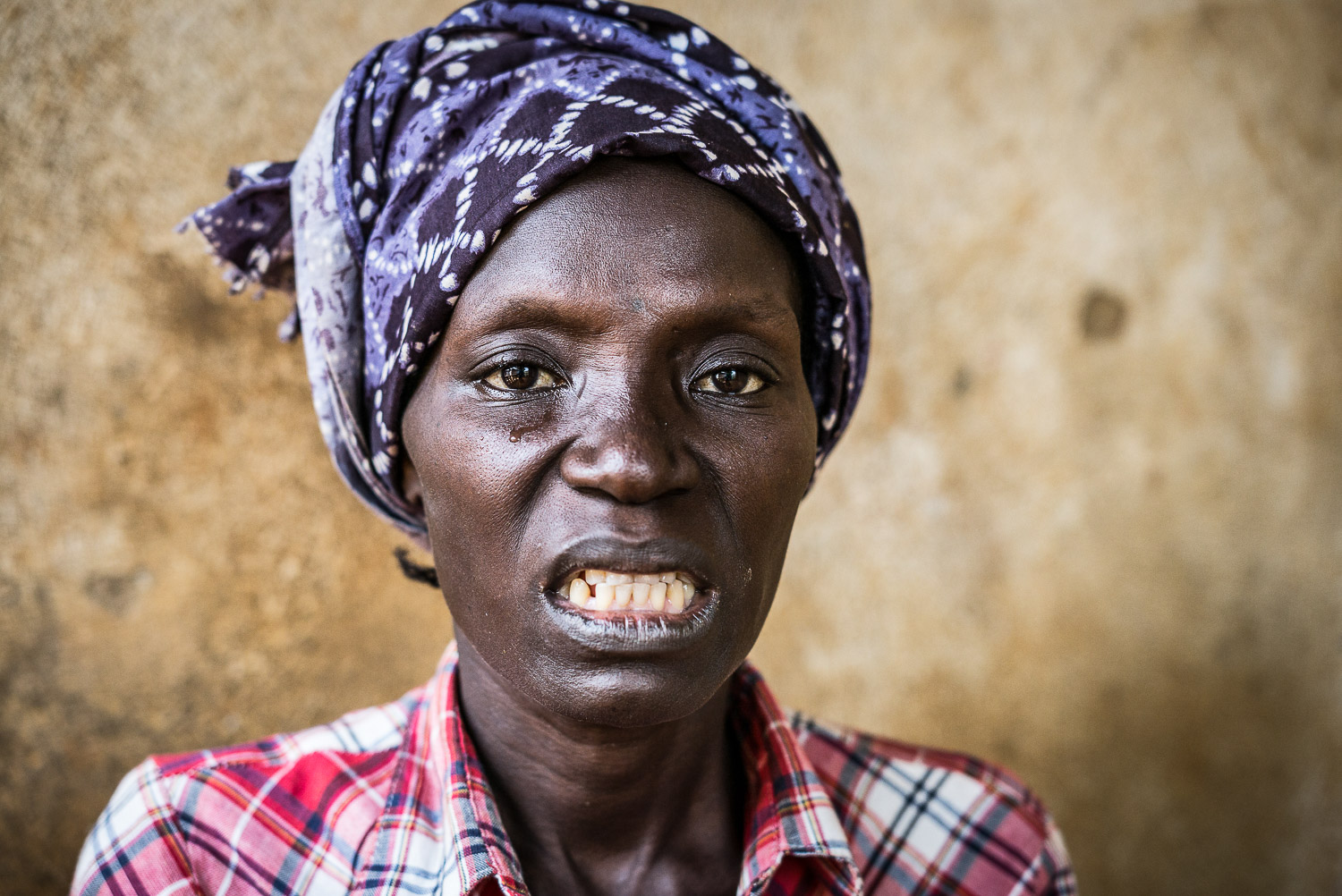 April 2017. Eye Gbakie grimaces in pain, waiting for her son Earnest to return home with some cassava root, the only food she is still able to consume. She had sent Earnest on an errand to find cassava at a local market 2 hours earlier, but he has n