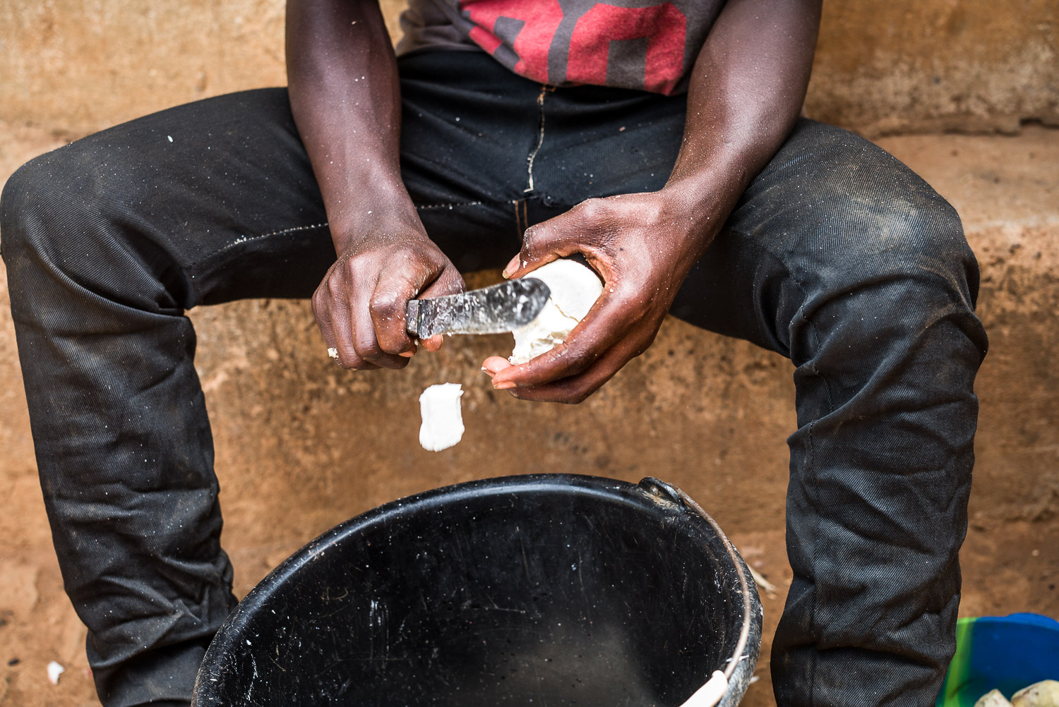 April 2017. The task of meal preparation has now fallen to the men in the family. Here, Wilfred, Michael and Eye's middle son, chops cassava root for a meal.