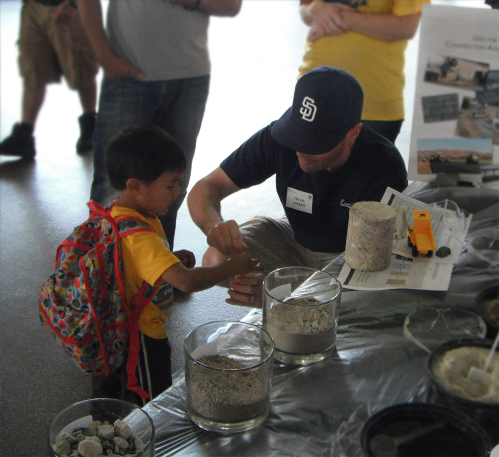 Travis Jokerst from EnviroMINE, Inc. helping a young boy mix concrete.