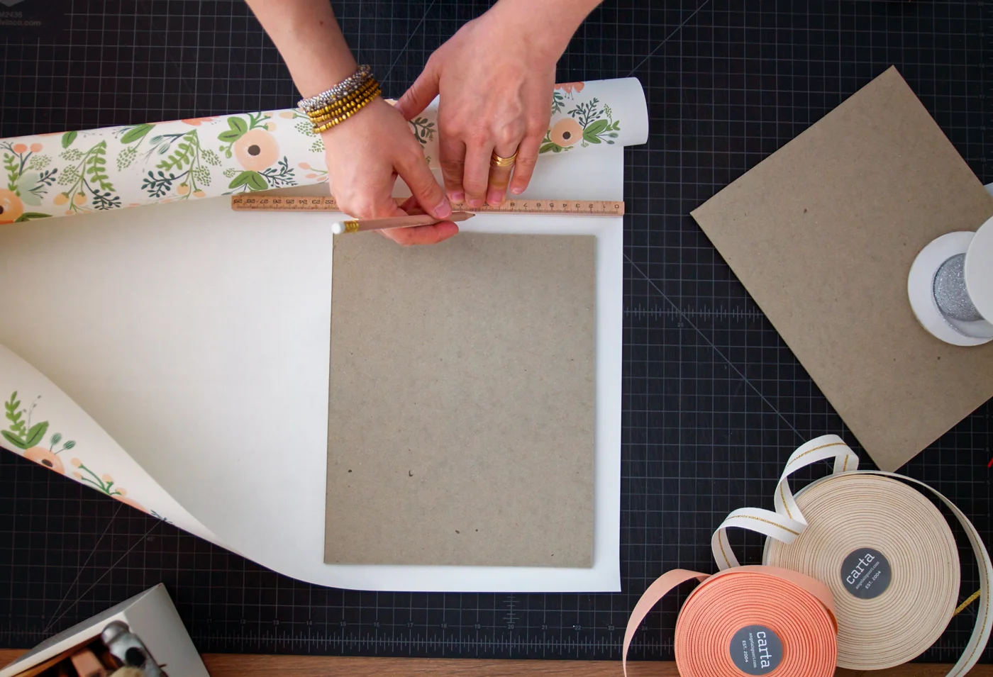 Step 1: If you have not already done so, cut your archival cardboard to the desired size. We chose 8×10. To create your outside cover, lay the cardboard onto your paper and, using this as a template, measure and mark your paper so that it is a couple centimeters, or about 1/2 inch, larger all around. Cut out your paper. Repeat for the other cover.
