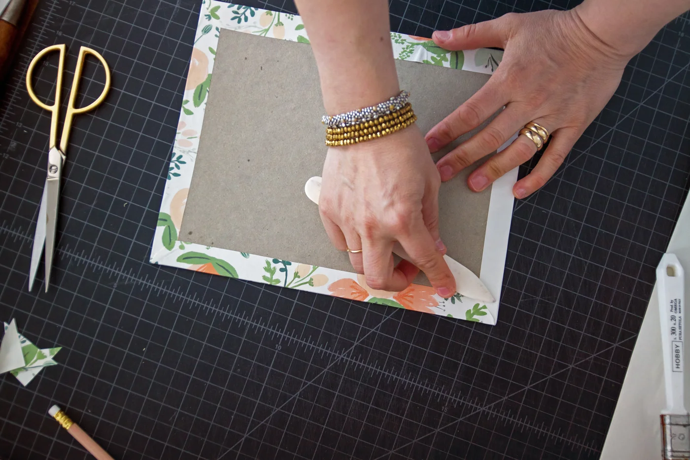 Step 5: When you are done, gently work out any air bubbles with your bone folder. Then lightly tap down on all your corners, so that your cover doesn’t have any sharp edges. Repeat this whole process with the next piece of cardboard.
