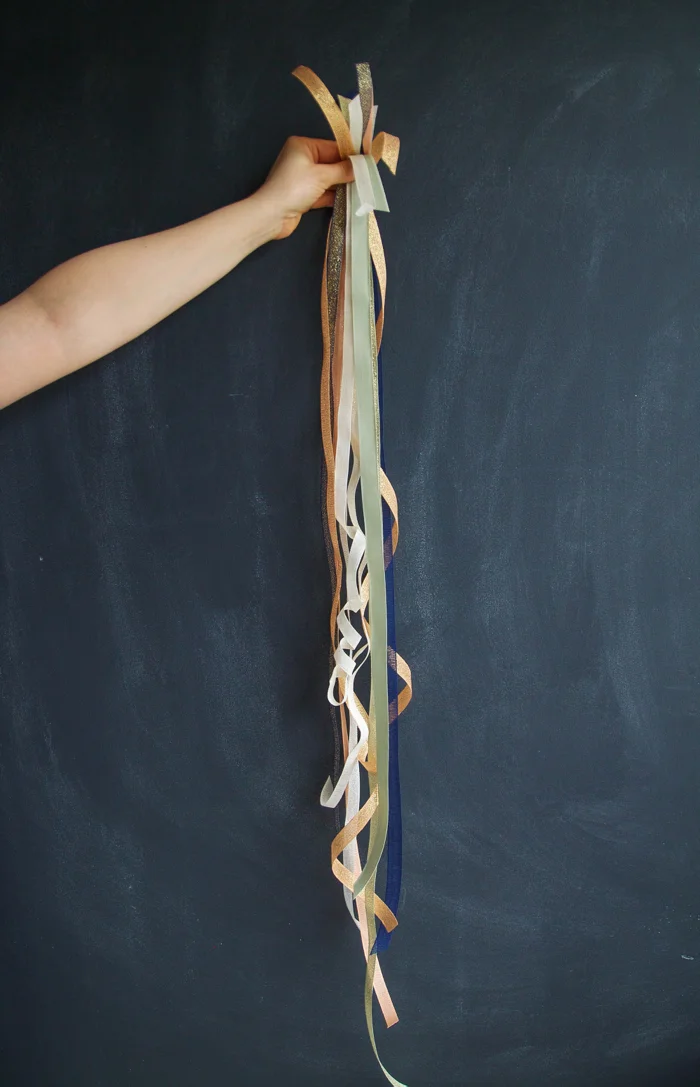 Step 4: Cut your ribbons to approximately the same length. Then using one-at-a-time, loosely wrap them around your garland. Rather they tying ours, we secured the ribbons be weaving them in and out of the greens.